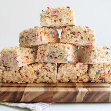 Finished treats are stacked 4 layers high on a wooden cutting board.