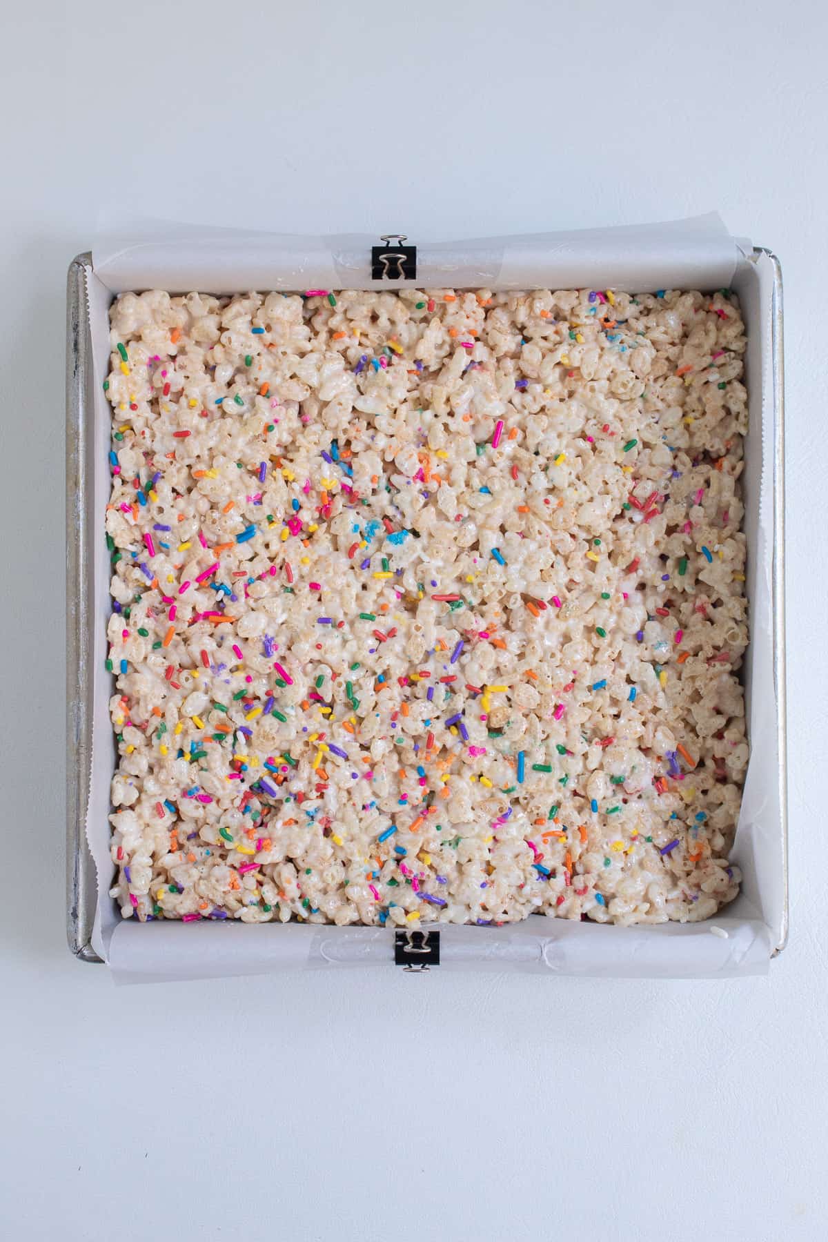 The rice krispie mixture is pressed into a square pan lined with parchment paper.