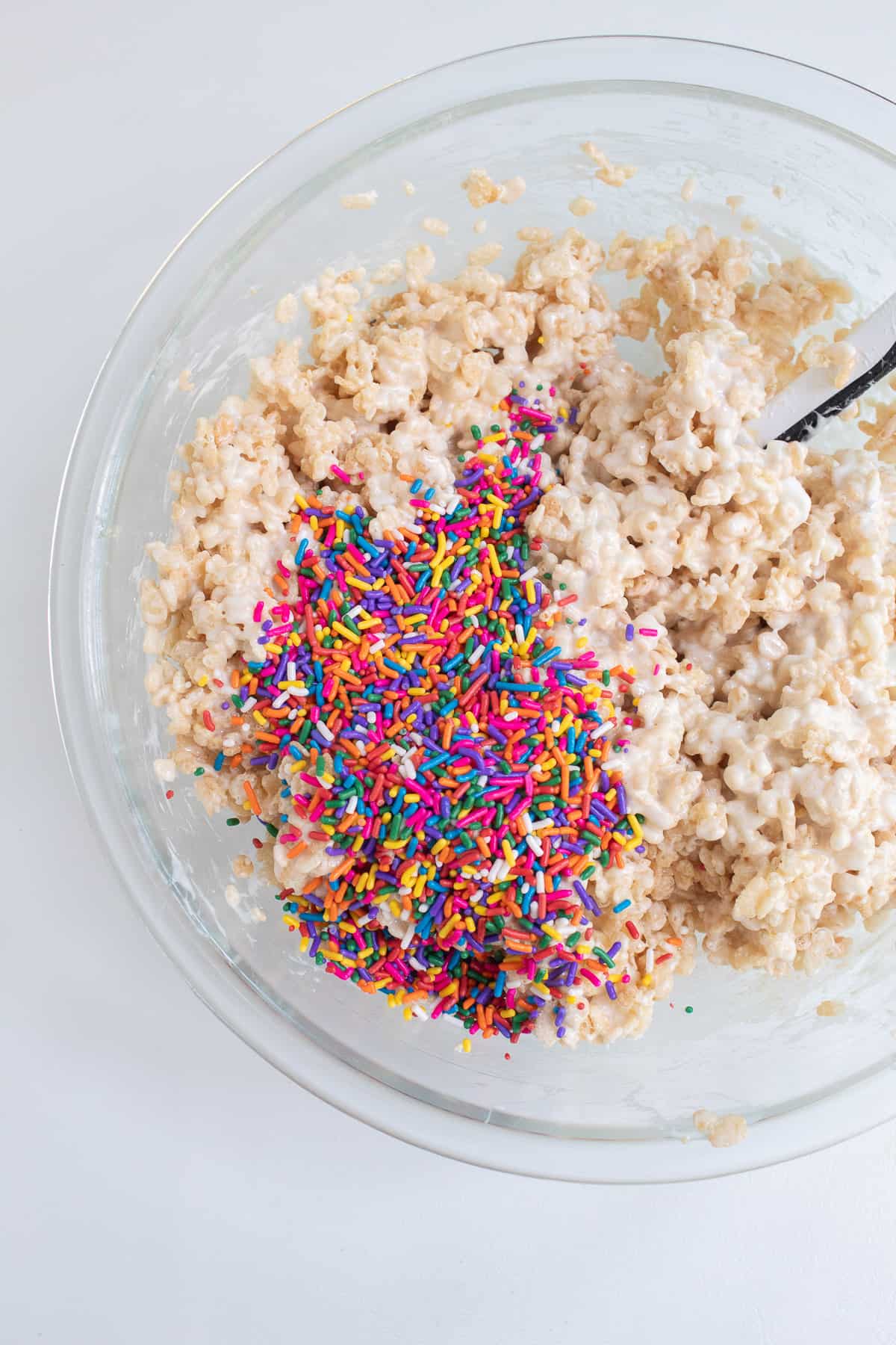 The multicolored sprinkles are poured over the marshmallow and cereal mixture.