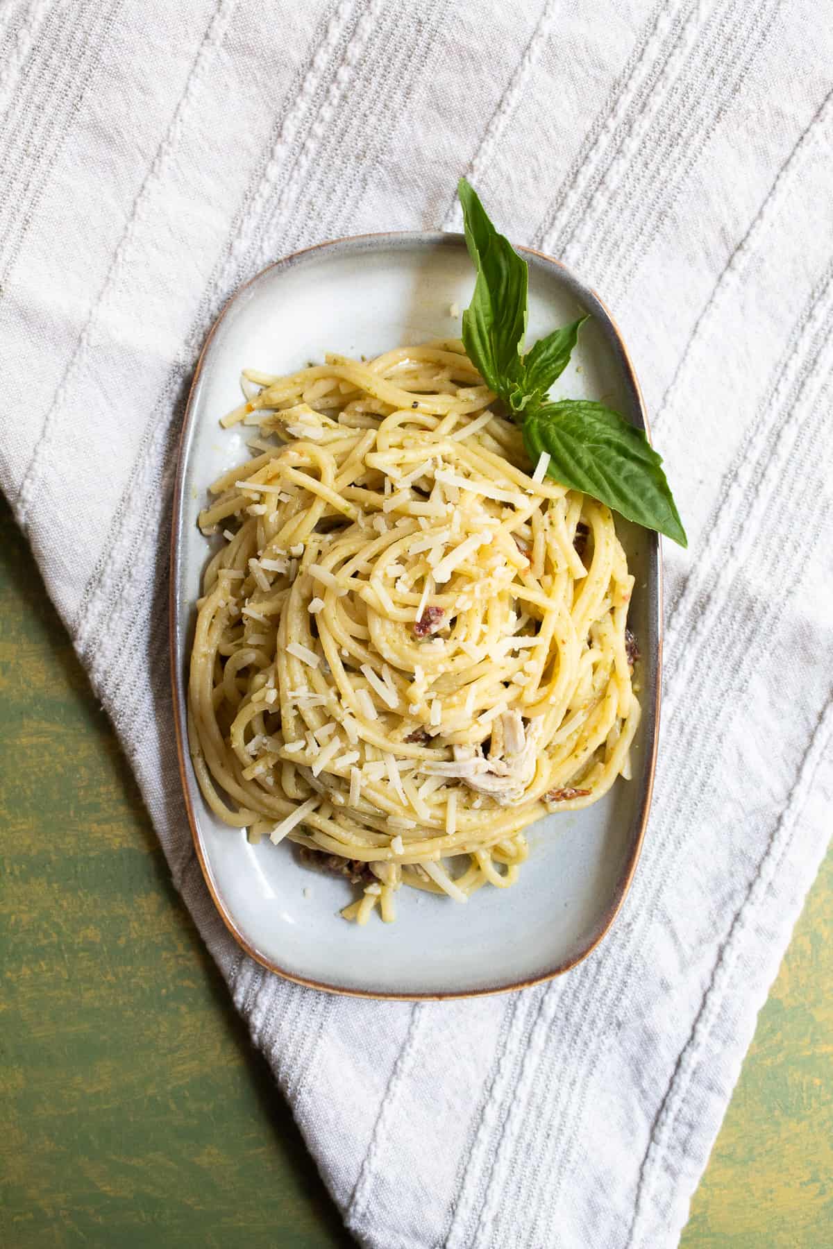 A serving of the spaghetti sits on a rectangular plate and is garnished with basil leaves.