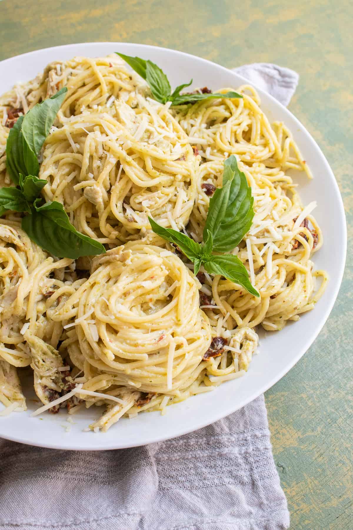 The spaghetti twirled into piles on a white platter and garnished with basil leaves.