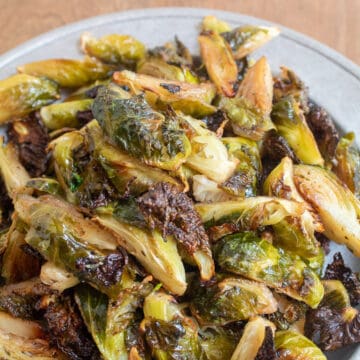 The finished brussel sprouts are golden and shiny and some of the pieces are caramelized and crisp looking.