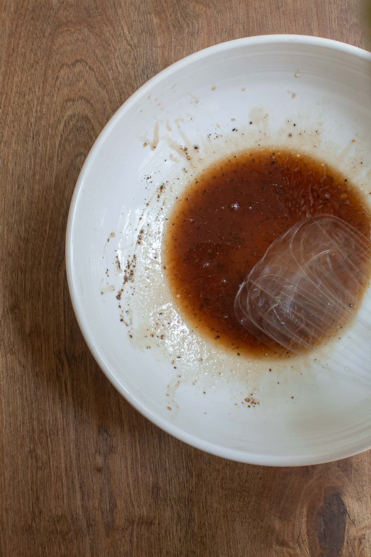 The glaze is being whisked in the bottom of a white bowl. The photo shows the motion of the whisk as a blurred object.