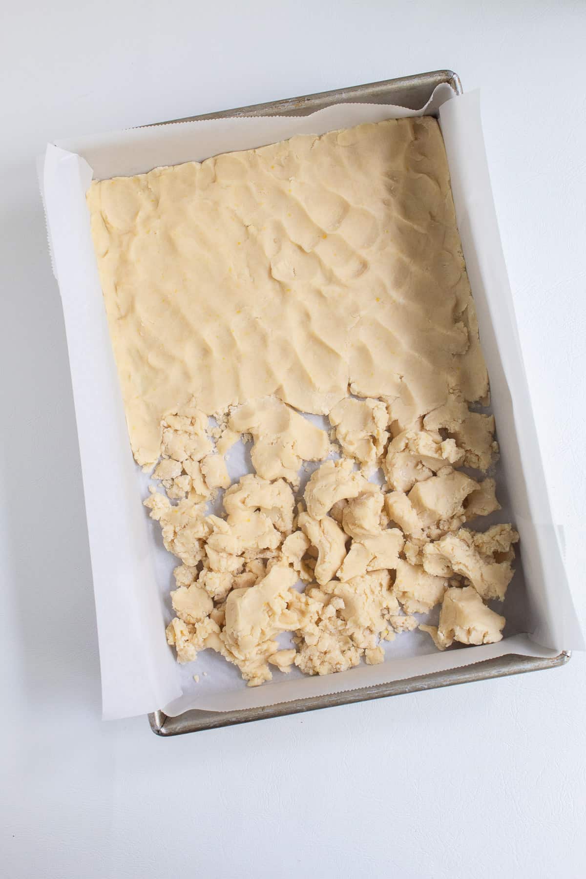 The shortbread mixture pressed into a parchment-lined baking pan.