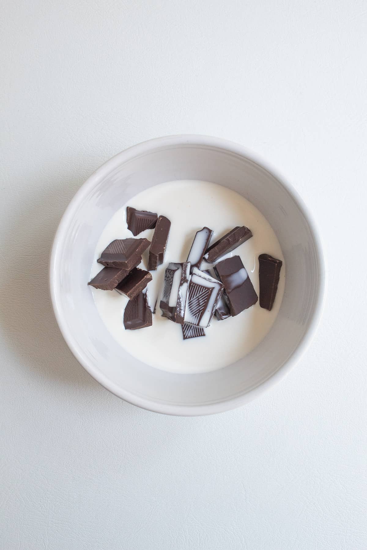 Cream and pieces of chocolate sit in the bottom of a small white bowl.