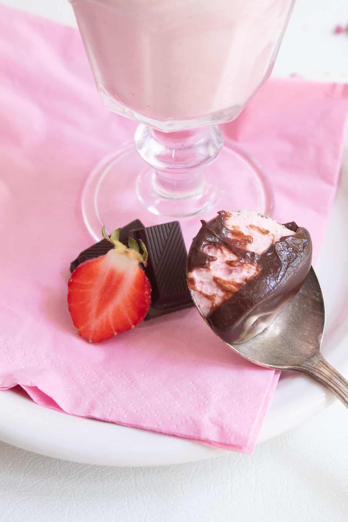 A detail image of a spoonful of the mousse with its soft chocolate layer next to a slices strawberry and pieces of dark chocolate.