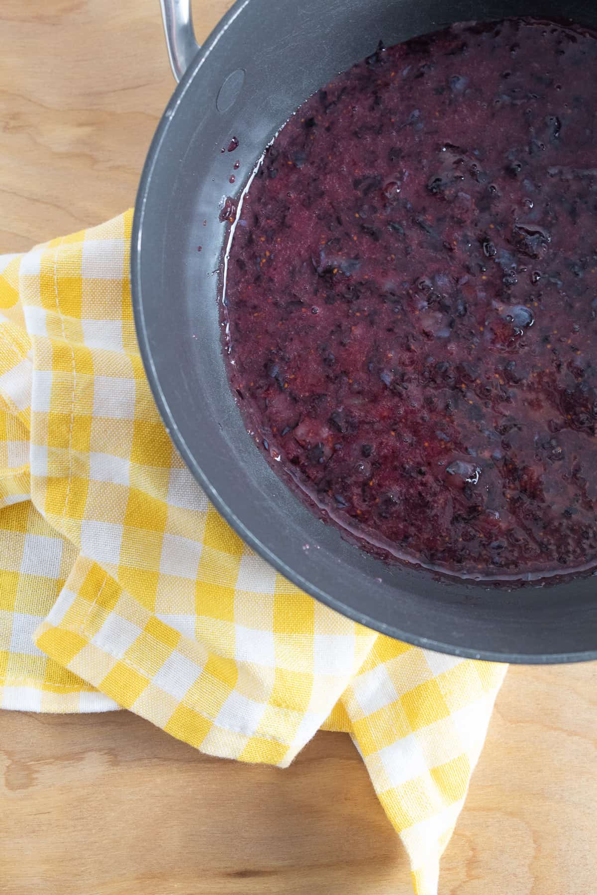 Pureed blueberries in the bottom of a dark sauce pan.