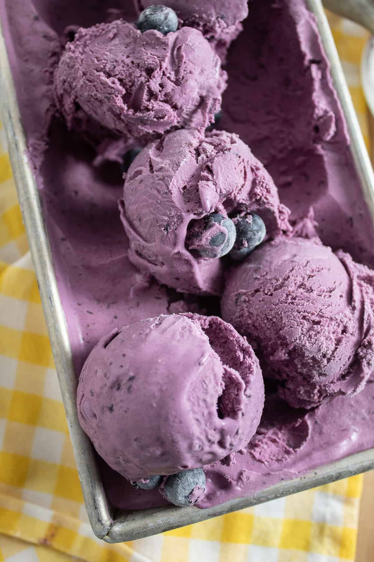 The frozen ice cream scooped in heaps in a loaf pan and sitting on a yellow checked napkin.