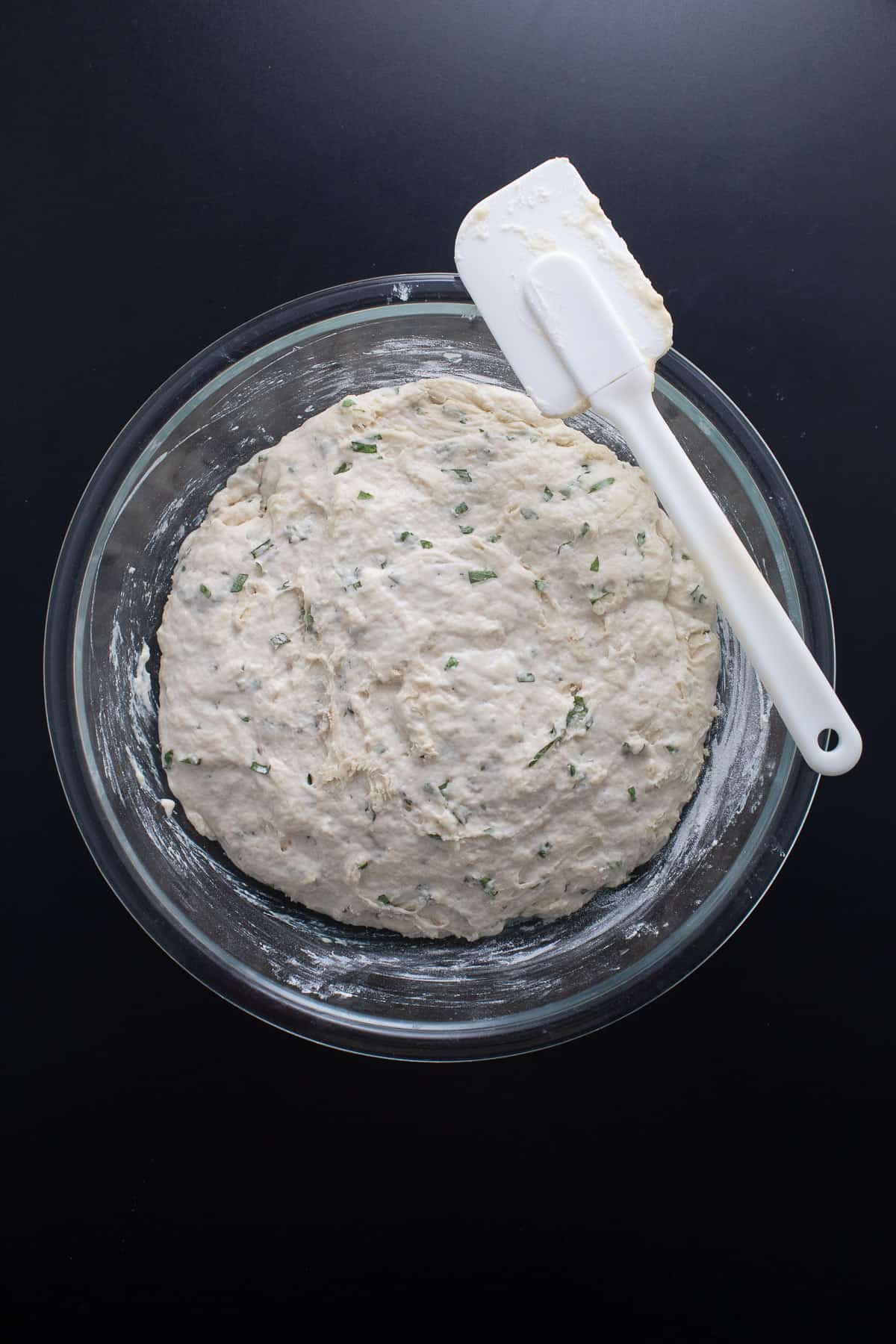 The dough sits in a large glass bowl after resting and is now doubled in size.