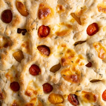 A detailed image of the baked focaccia with a browned top and sunken tomatoes.