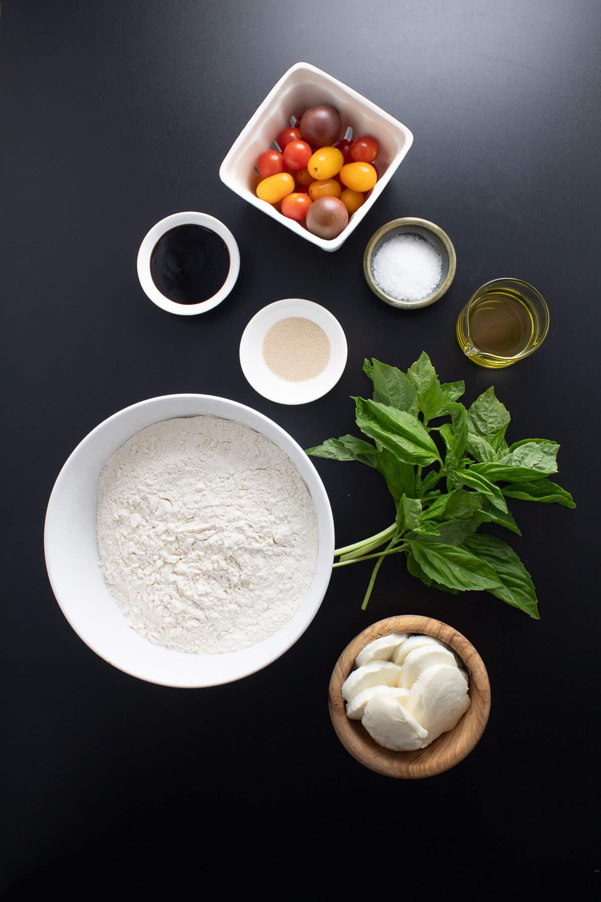 Ingredients for the bread are arranged on a black surface.