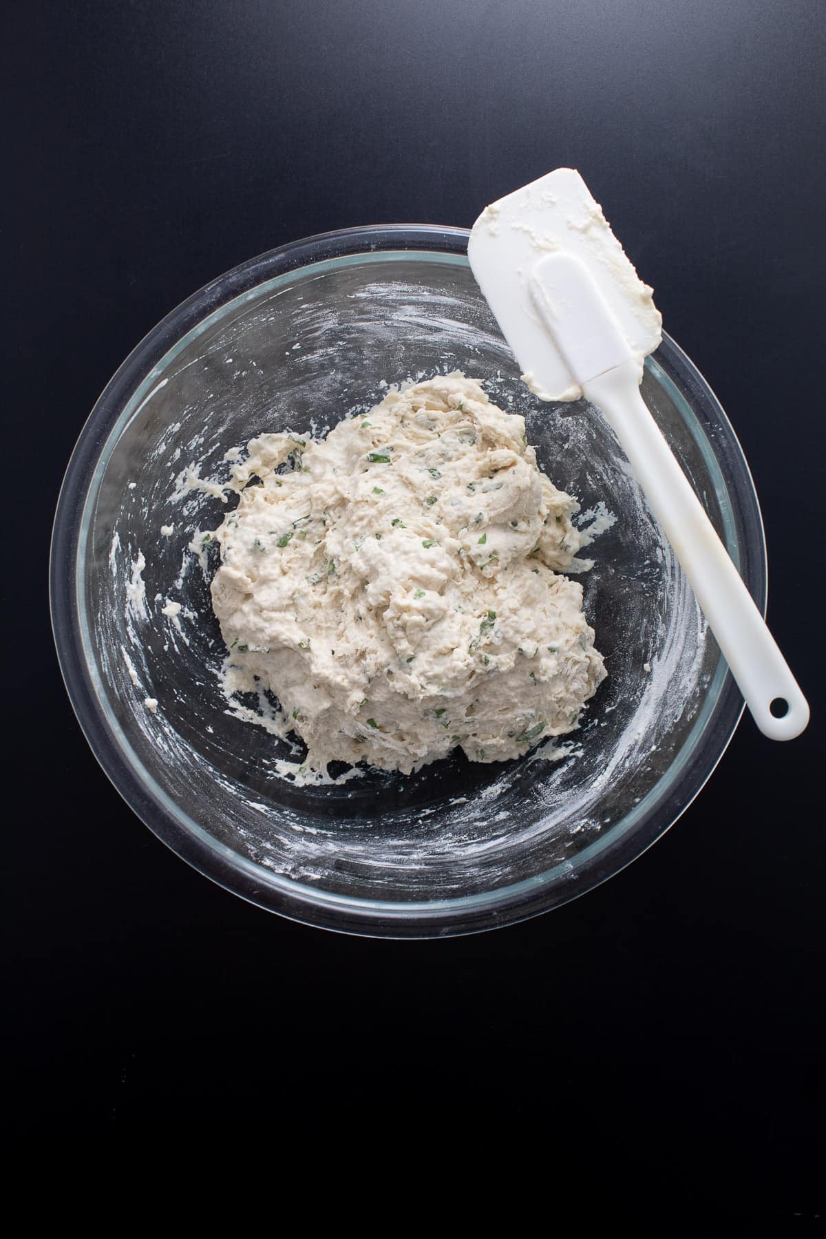 The focaccia dough mixed together in a clear glass bowl.