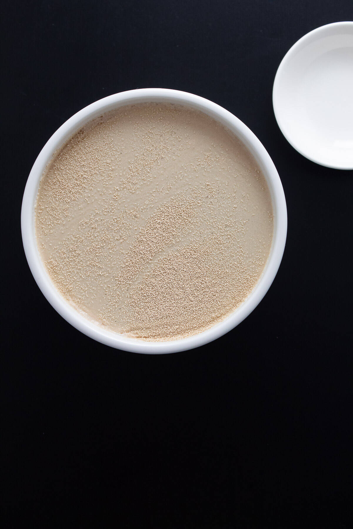 Yeast sprinkled over water in a bowl.