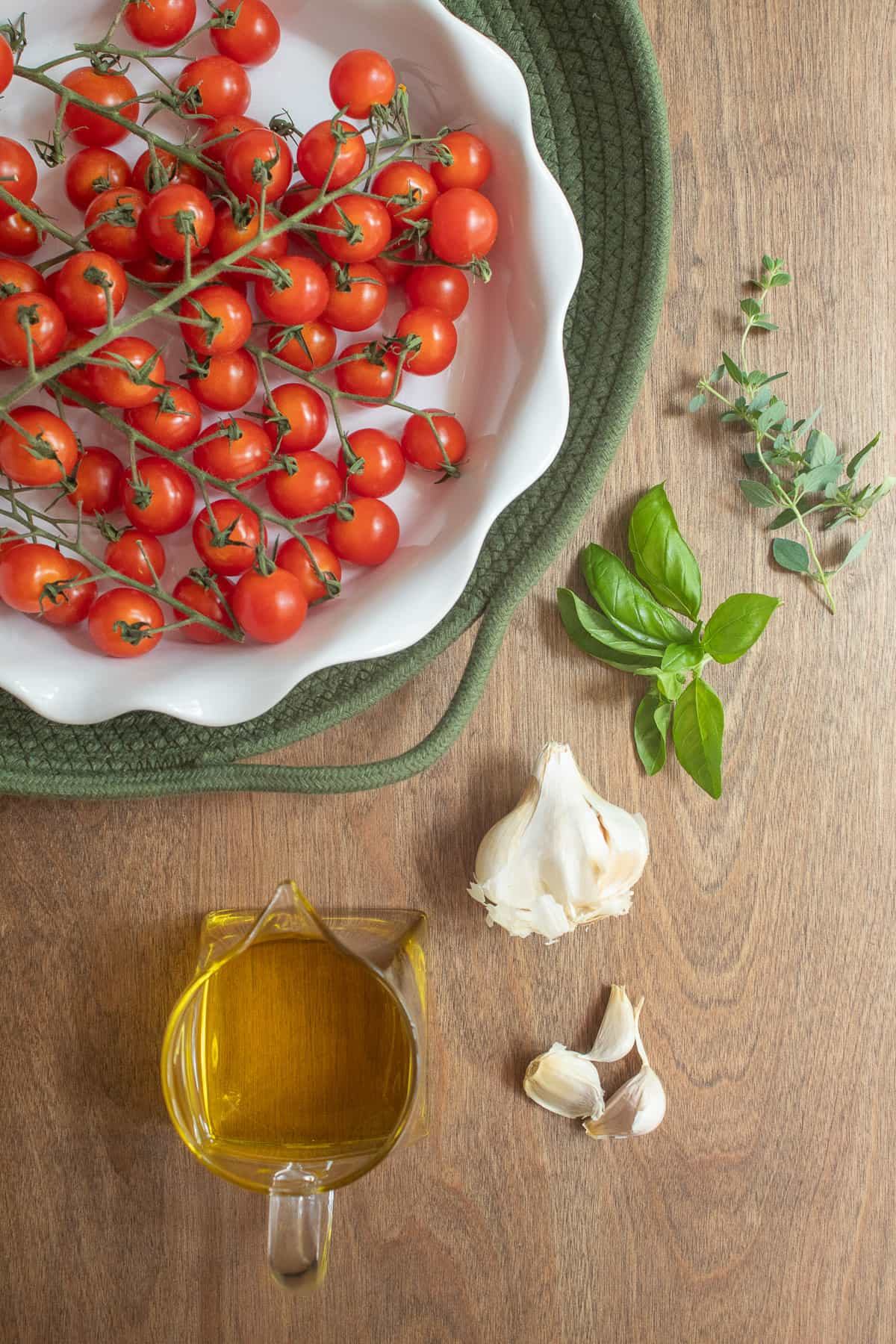 The ingredients for the cherry tomato confit arranged on a wooden surface.
