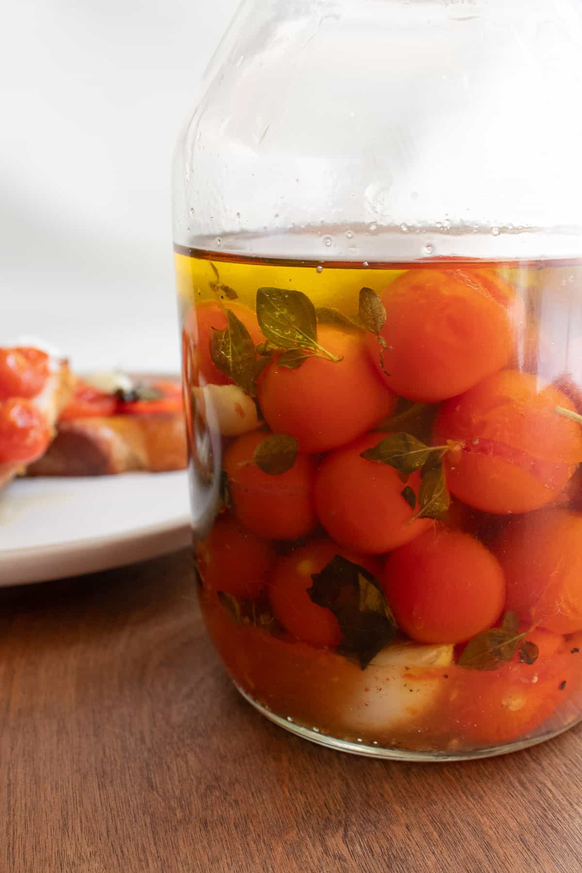 The cherry tomato confit and oil stored in a clear glass jar.