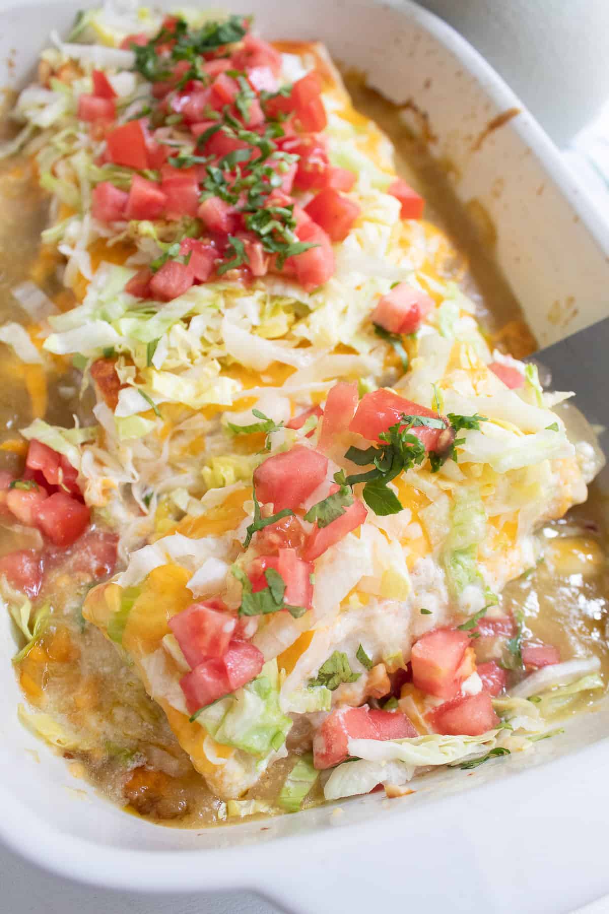 A serving of the burrito casserole is lifted from the pan.