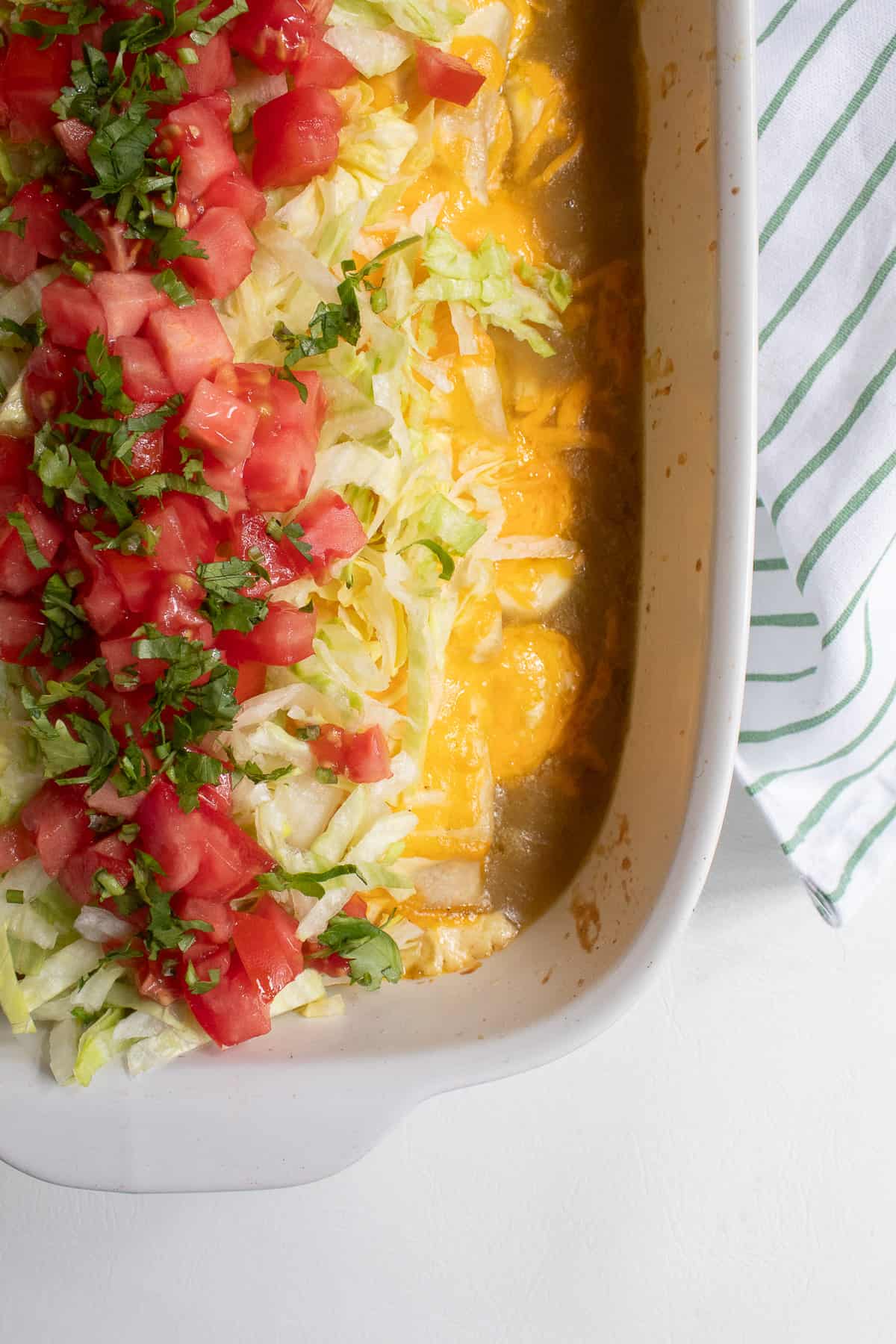 A detail image of the baked casserole topped with shredded lettuce, tomatoes, and cilantro.