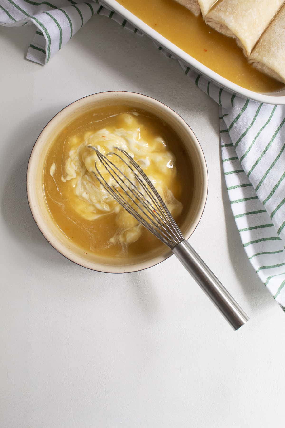 Green enchilada sauce and sour cream are whisked together in a medium bowl.