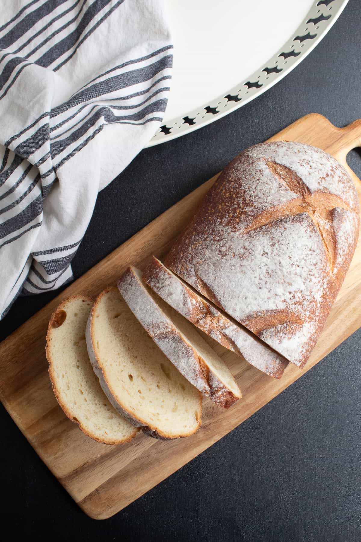 A loaf of bread is cut into 1-inch slices on a wood cutting board.