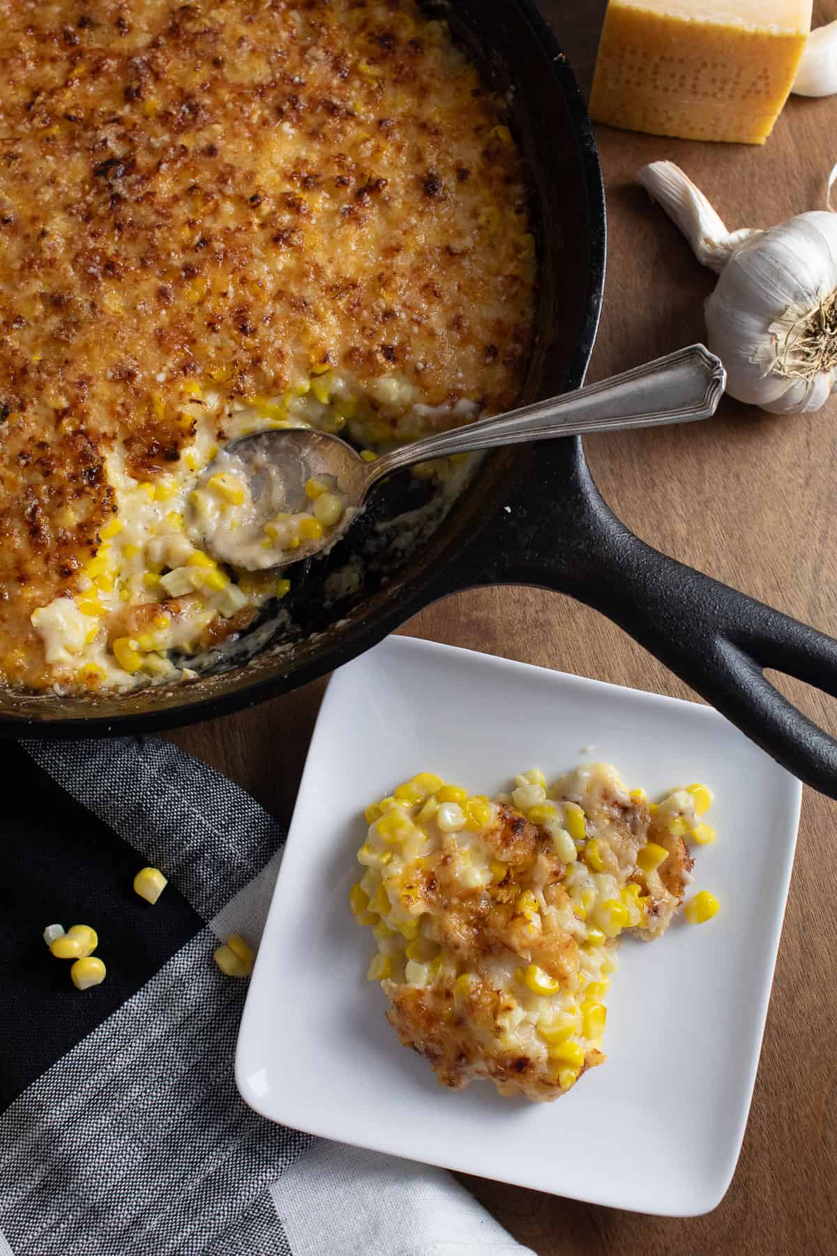 A serving of the corn au gratin is removed from the golden-topped casserole in a black skillet.