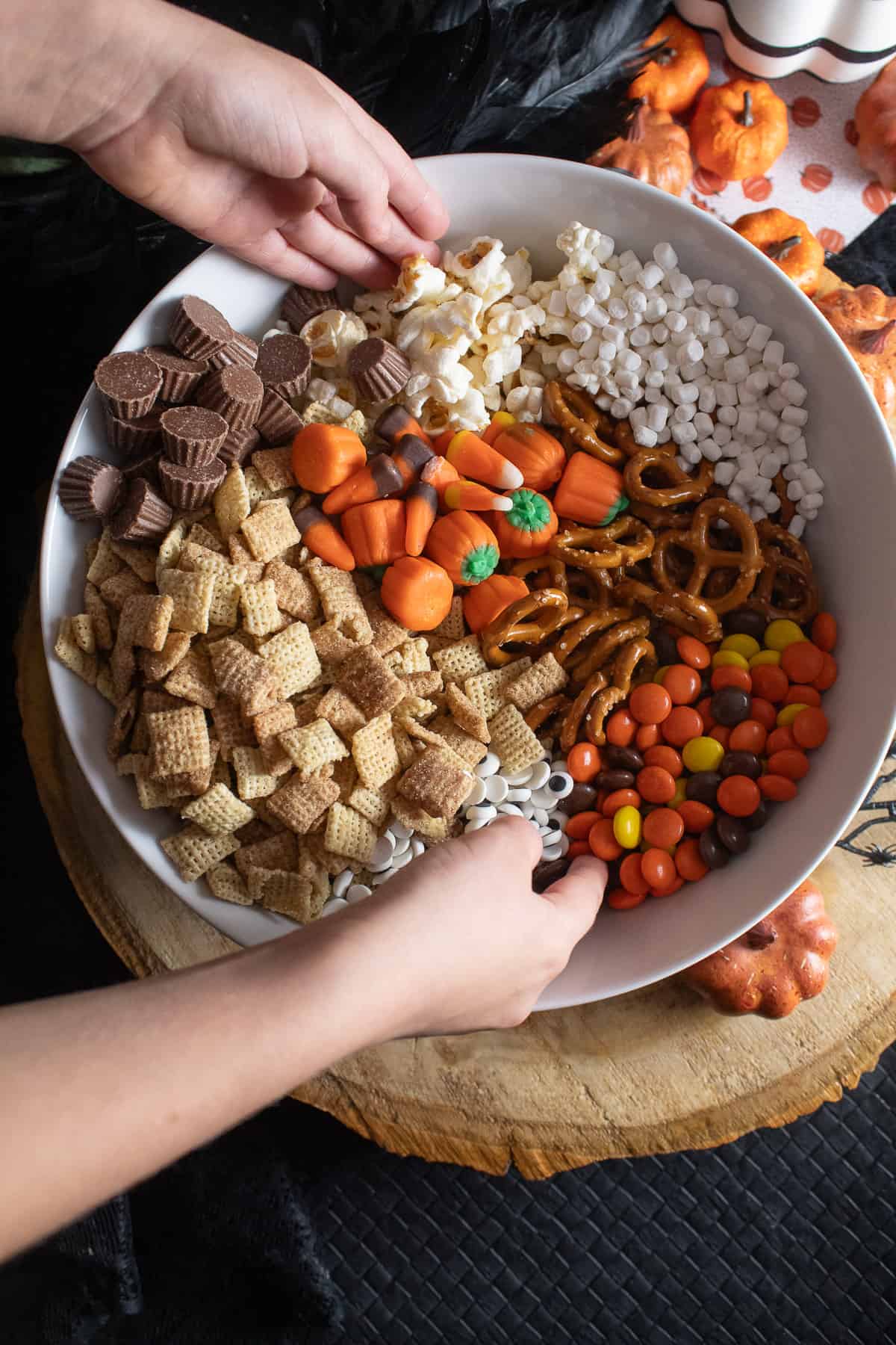 A child's hands are preparing to mix the ingredients together by hand in a large white bowl.