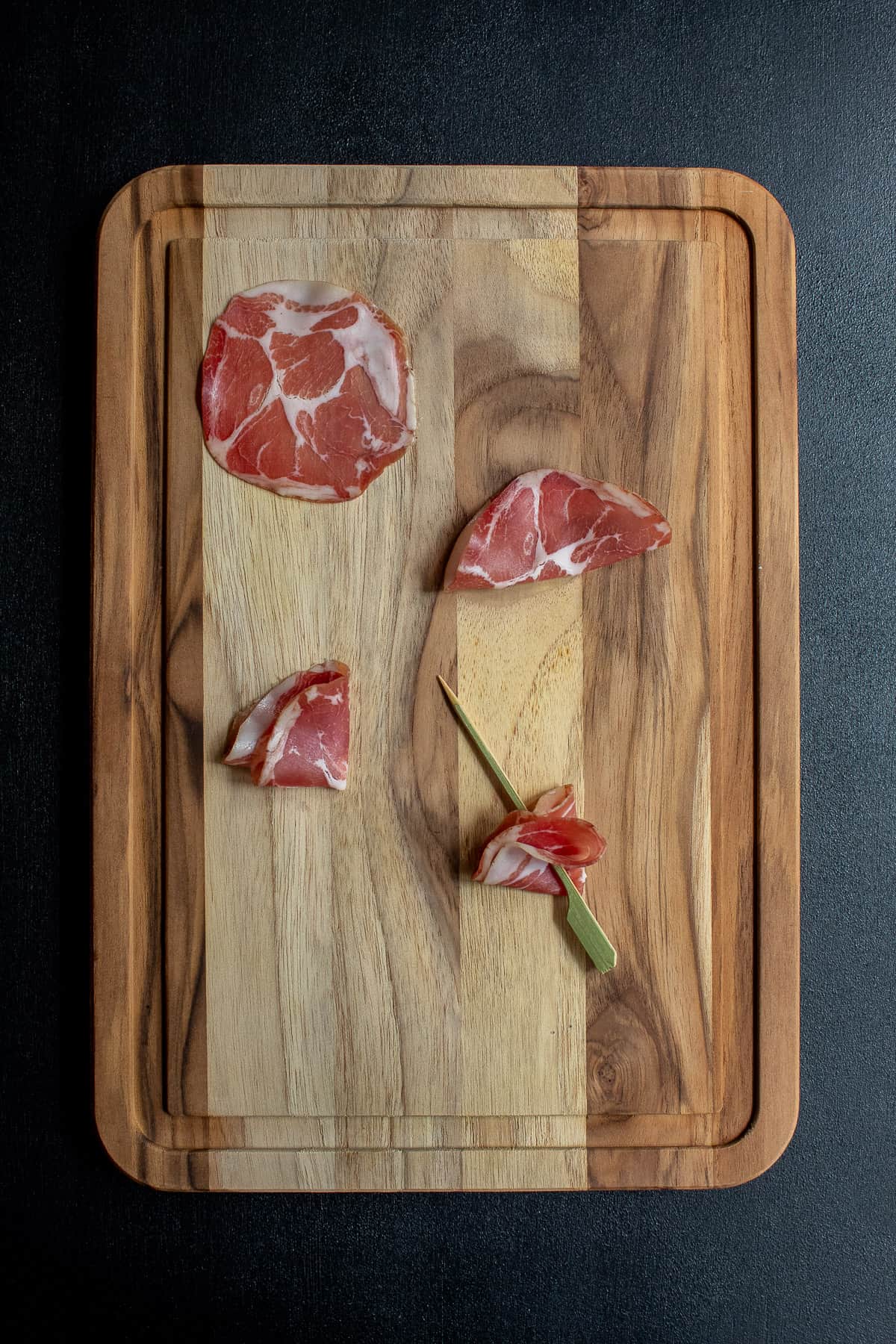 Steps for creating a coppa fan on a skewer are illustrated on a wood cutting board.