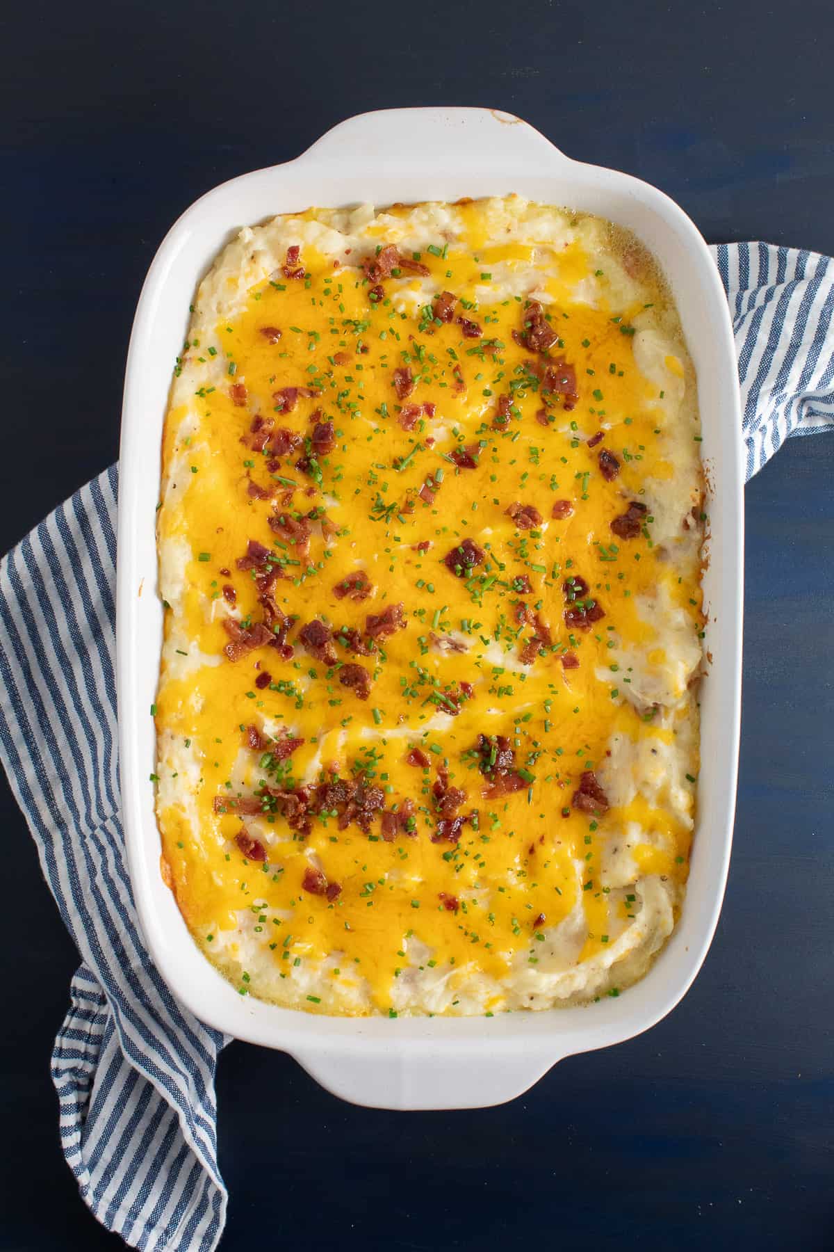 The baked casserole is covered with melted cheese and sits on a blue surface.