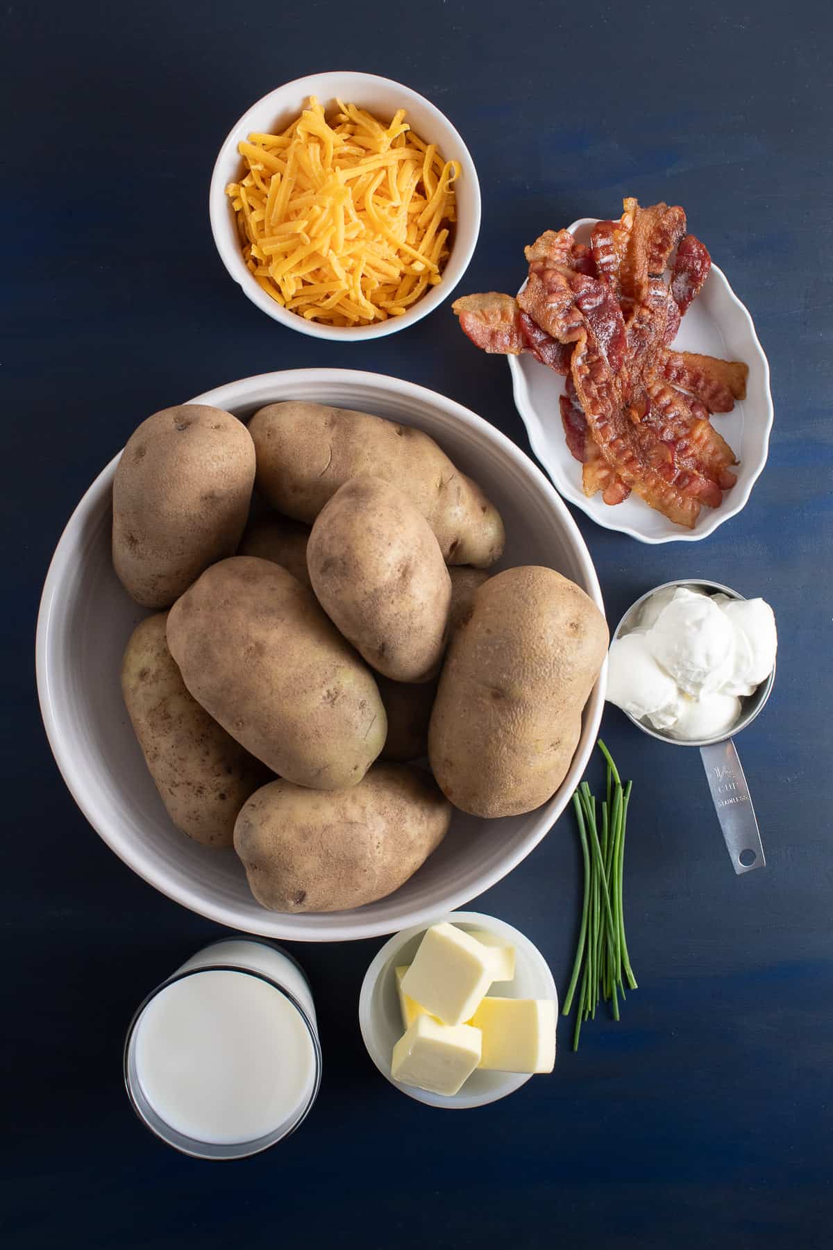 Ingredients for the baked mashed potato casserole are displayed on a blue surface.