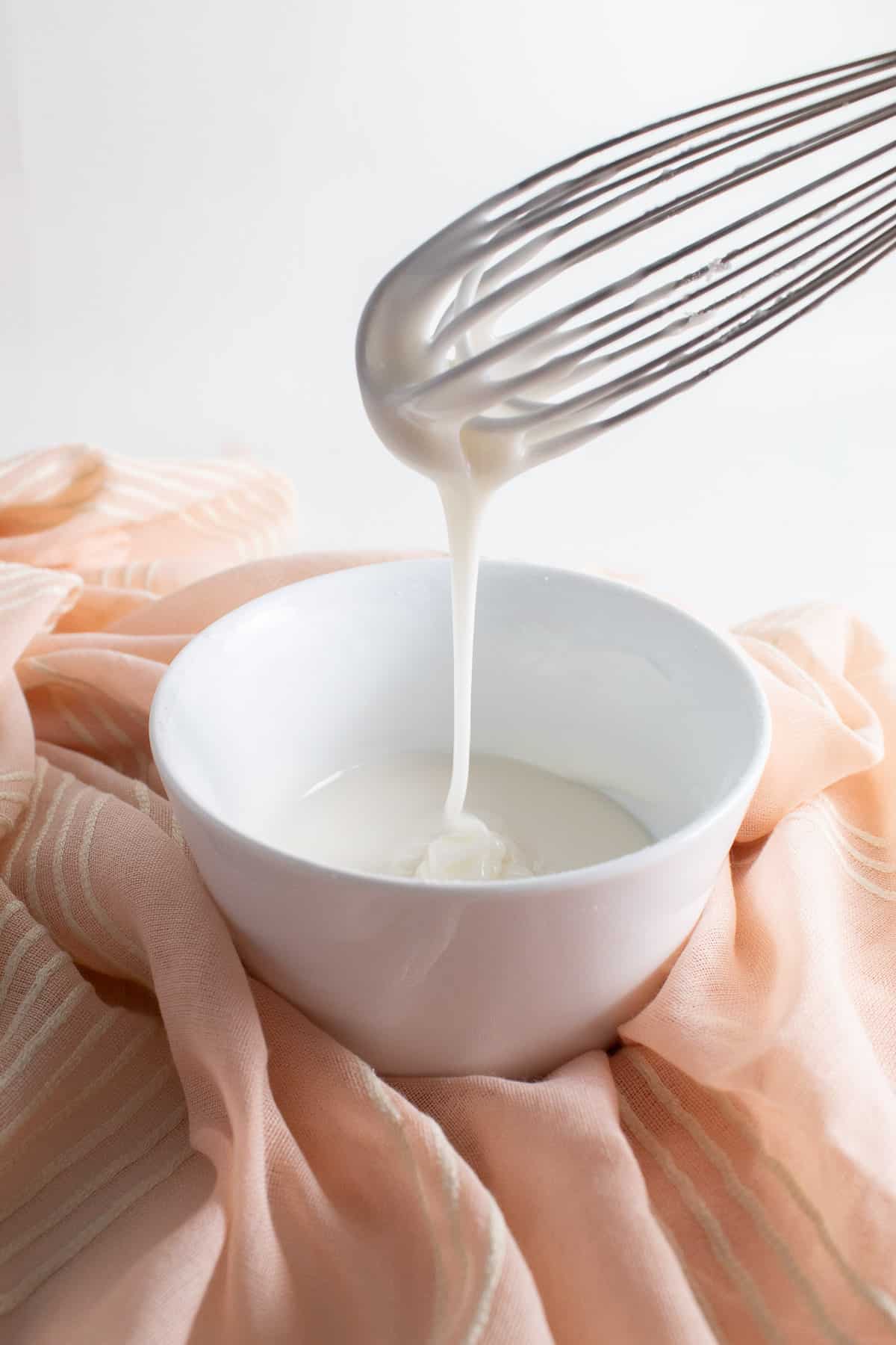 The correct consistency of glaze falls in a rope from the whisk rather than a sheet.