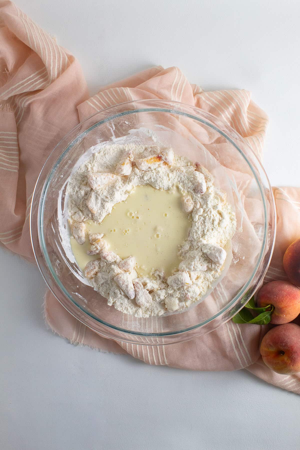 A well was created in the butter, peach, and flour mixture and the wet ingredients are poured into the well.