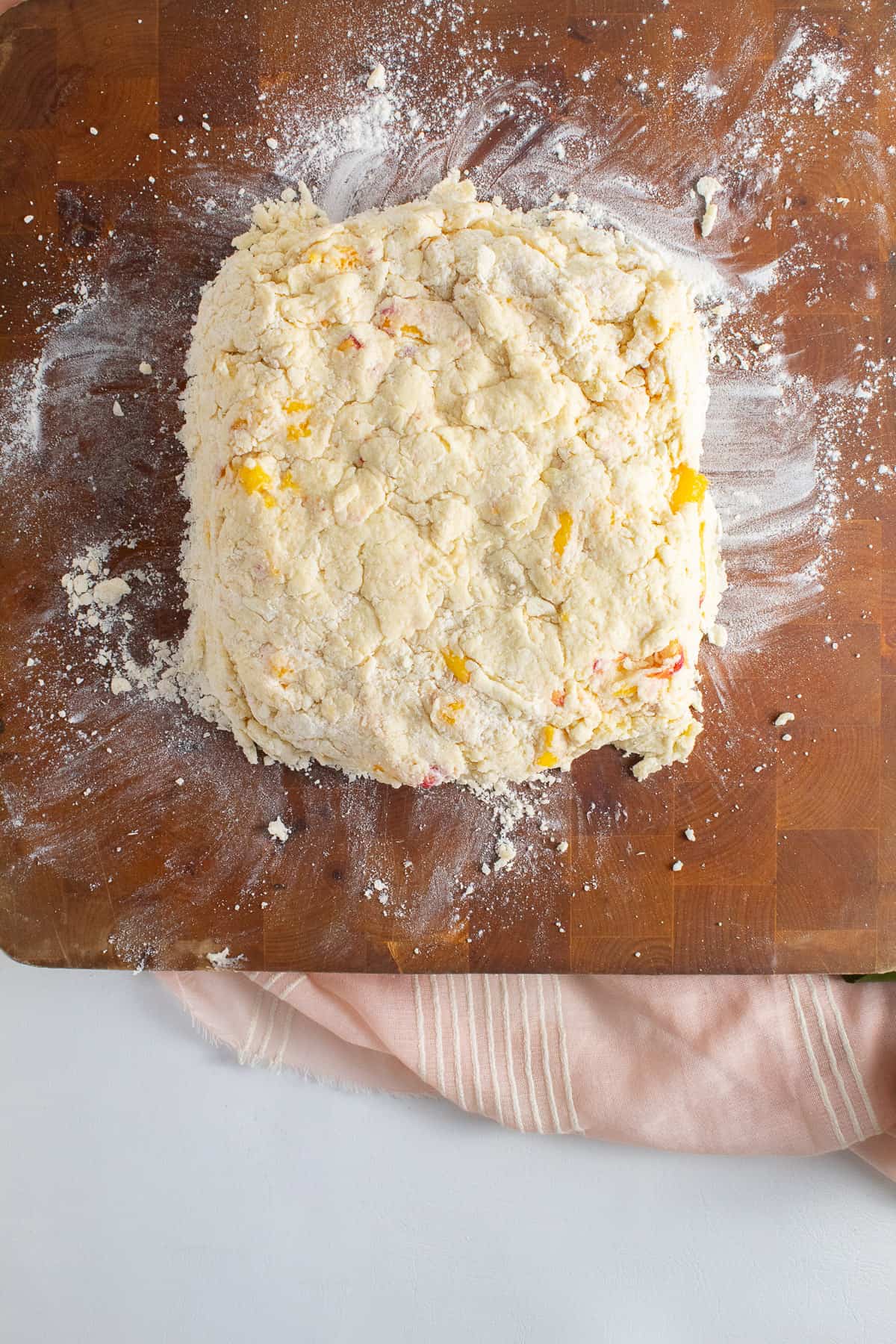 The biscuit dough is pressed into a rough square on the work surface.