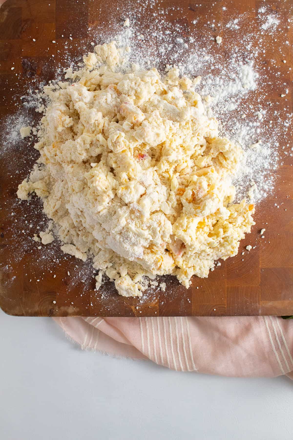 The crumbly dough is placed on a wooden work surface that has been dusted with flour.