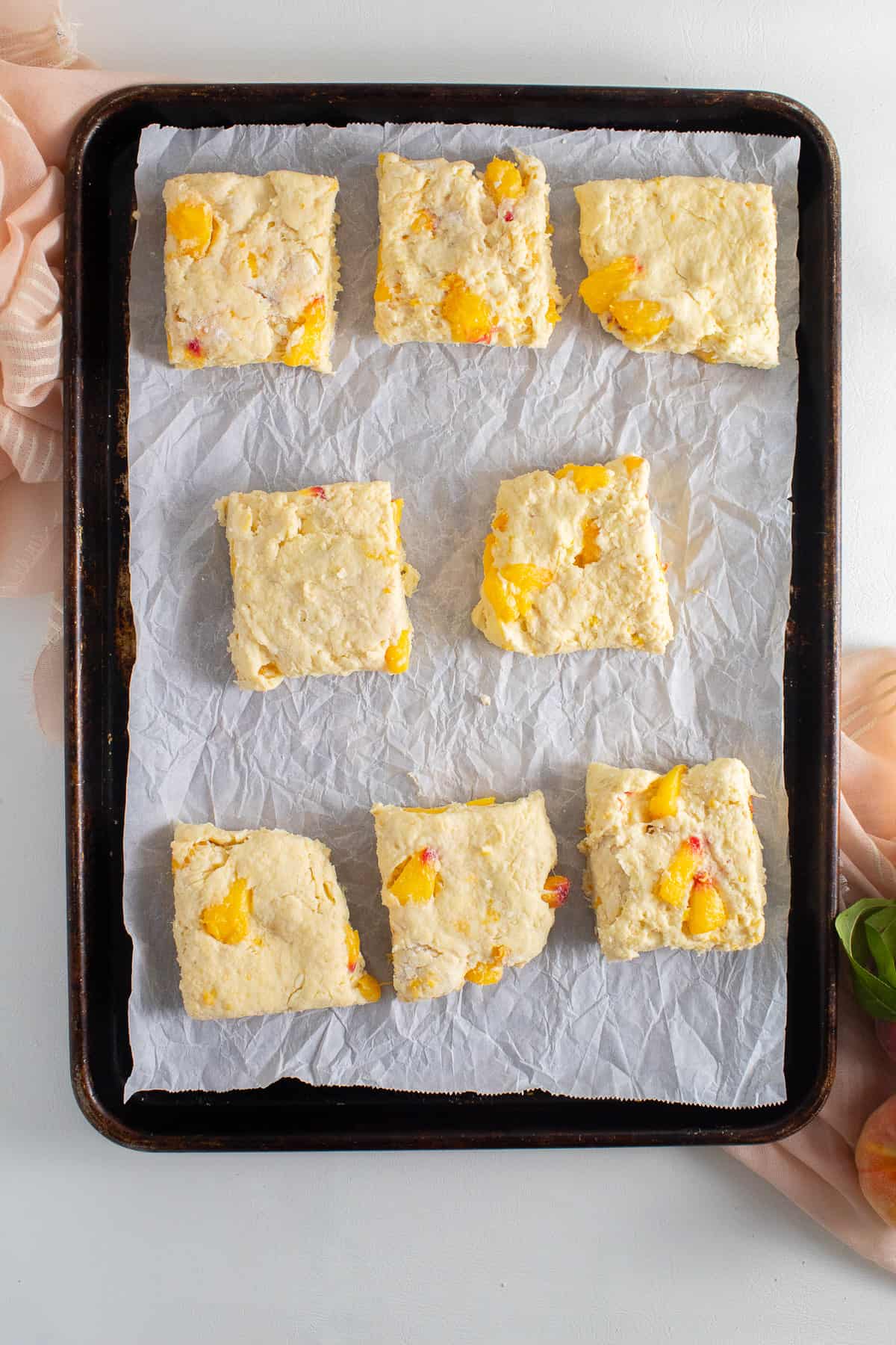 The cut biscuits are arranged on a parchment-lined sheet pan.