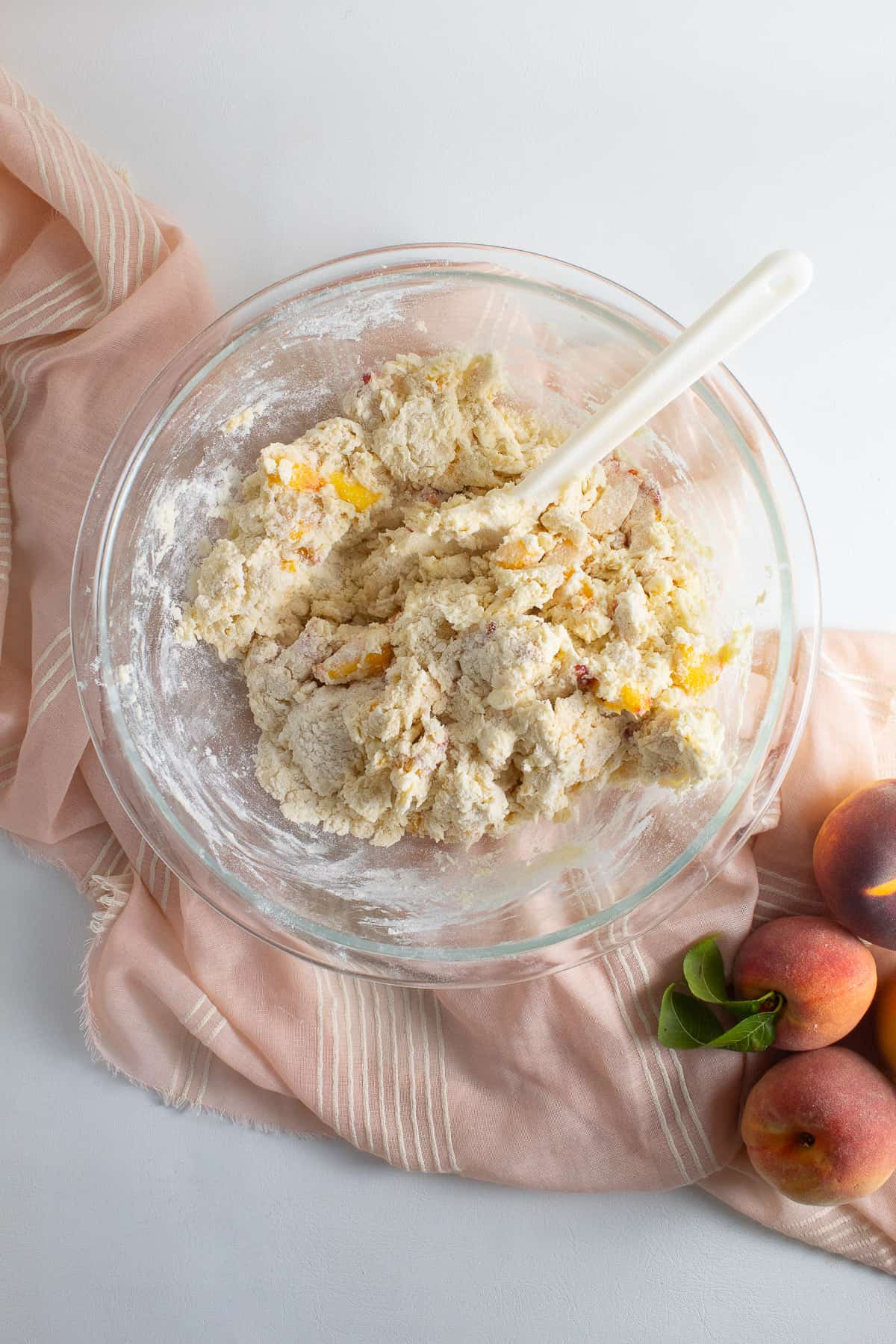 The wet ingredinets have been stirred into the dry ingredients to make a shaggy dough in the bottom of a large glass bowl.