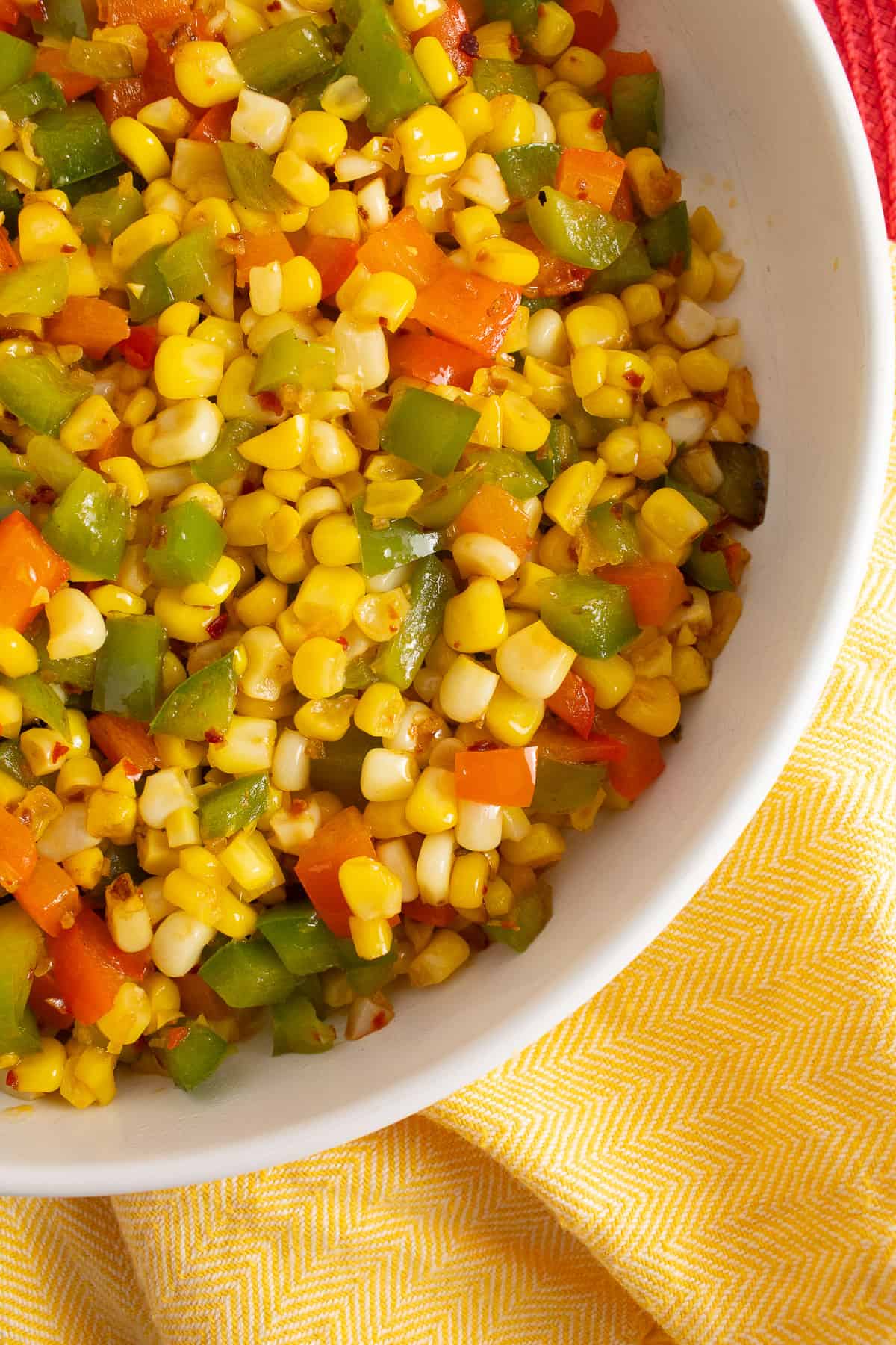 The finished side dish is served in a large white bowl on a yellow fabric surface.