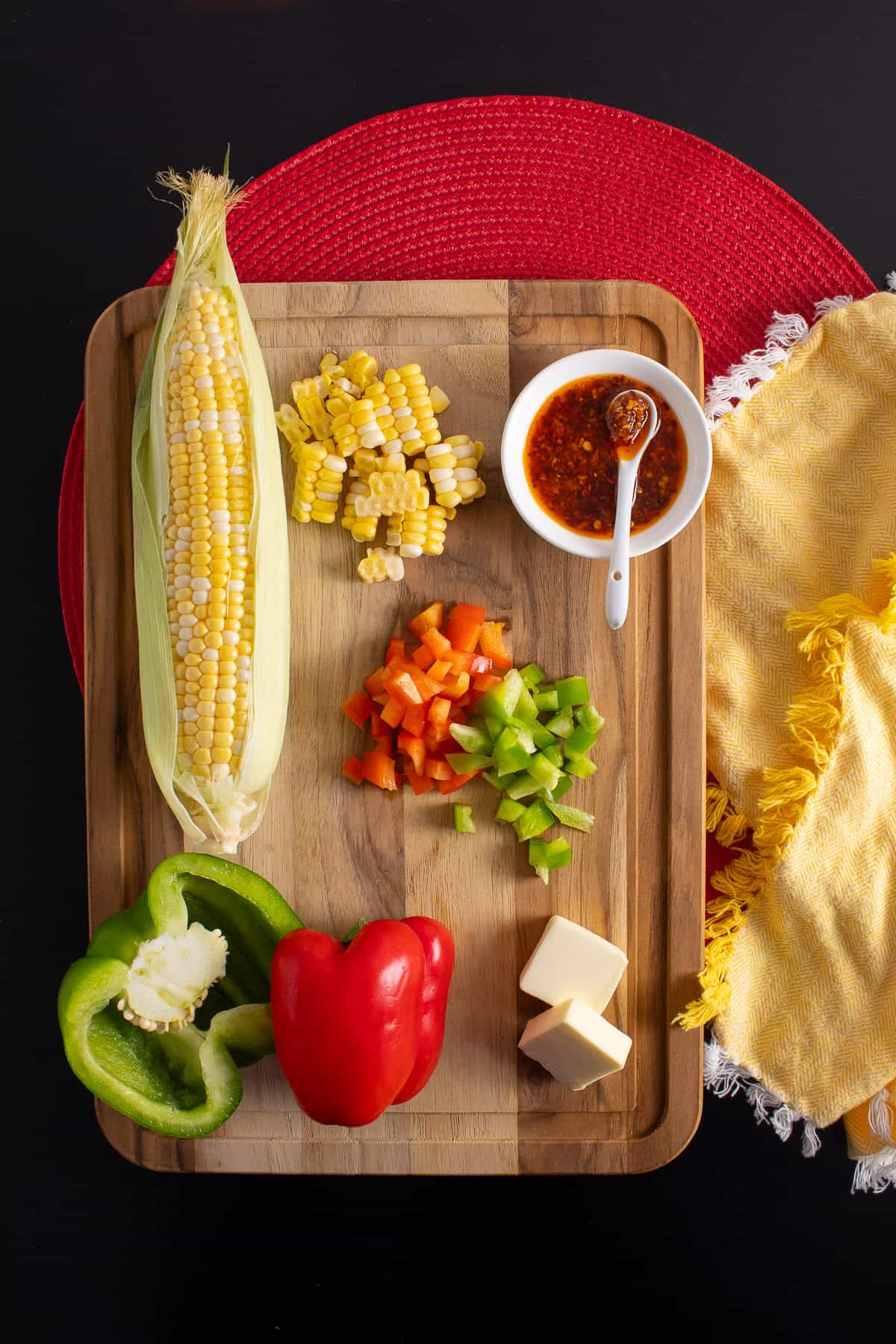 Ingredients for the corn sauté are arranged on a wooden cutting board.