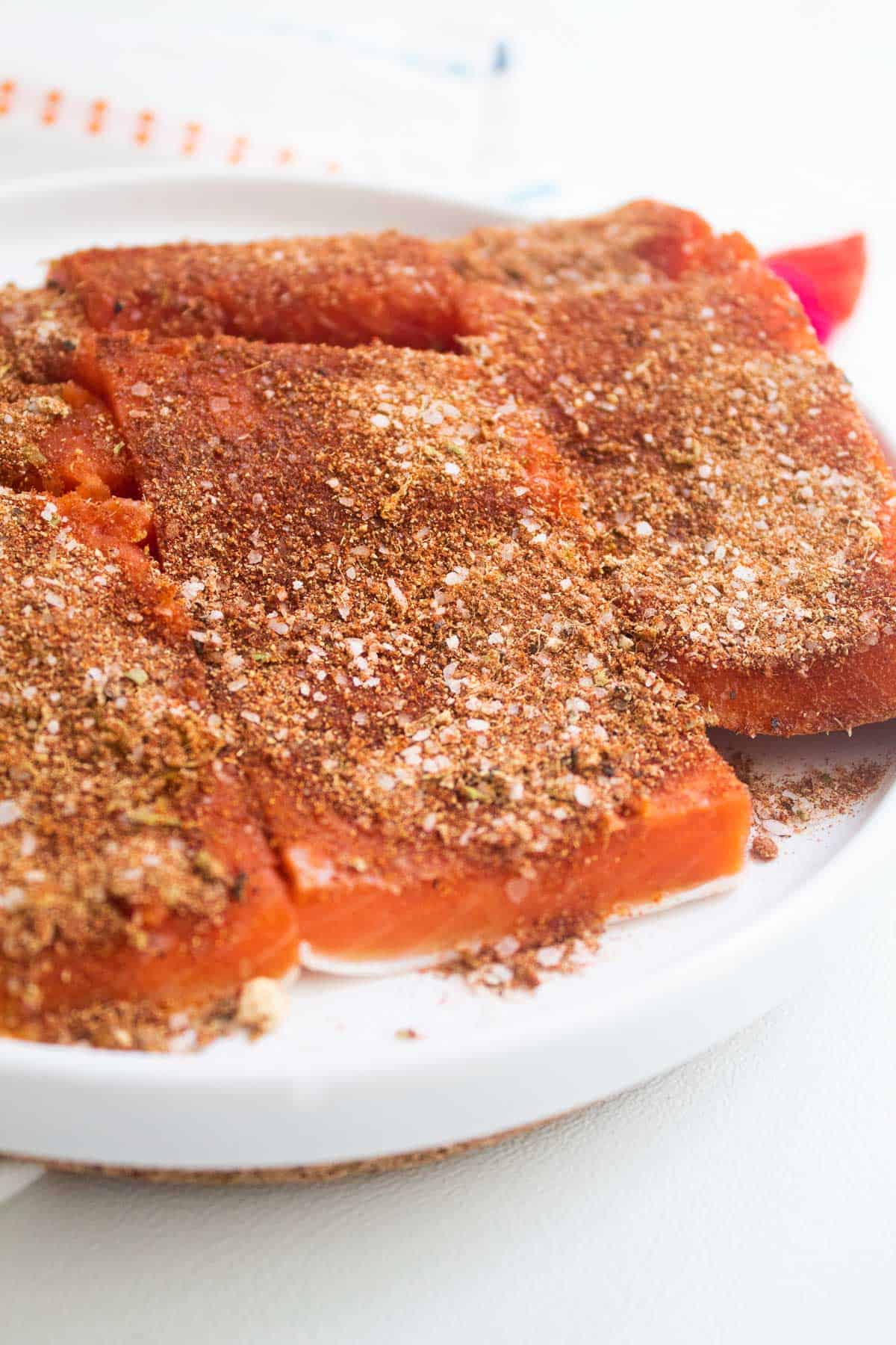 A detail image of filets of salmon rubbed with salt and a blend of spices.