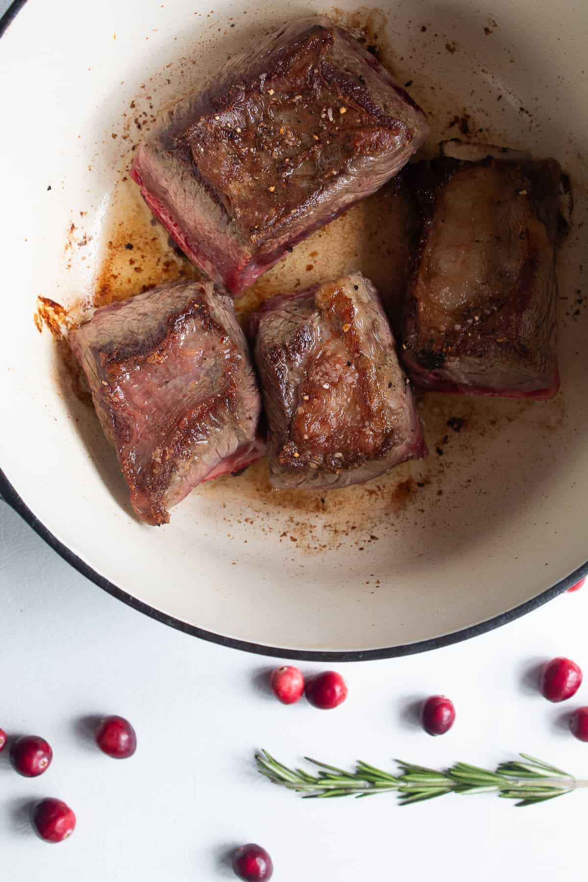 The short ribs are browned on both sides in the bottom of a large pot.