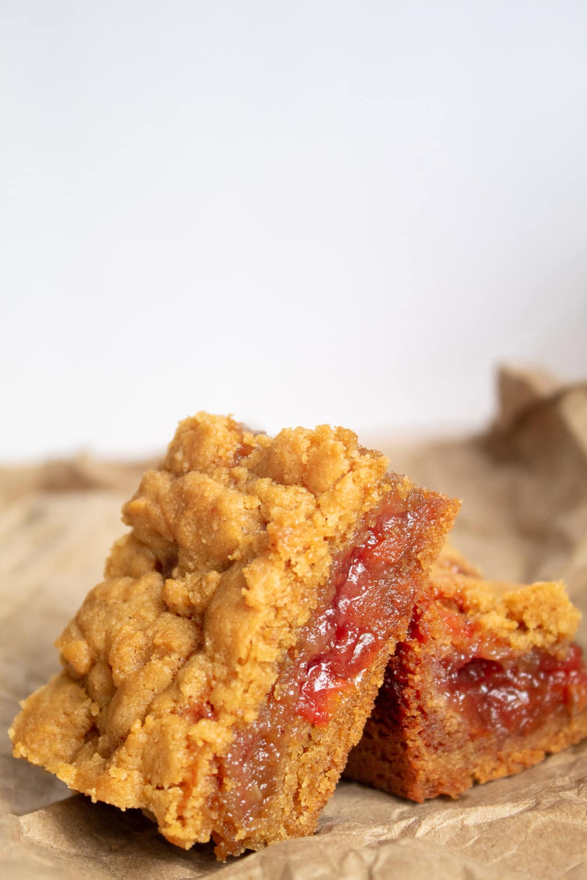 A detail image of the bars, highlighting the red jam layer and the soft peanut butter cookie layers.