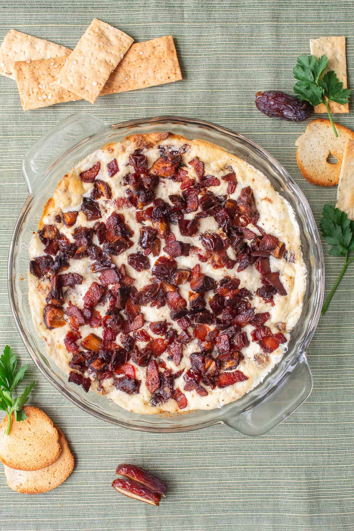 The baked dip has crisp bacon and dates on the top and a lightly golden color along the edges.