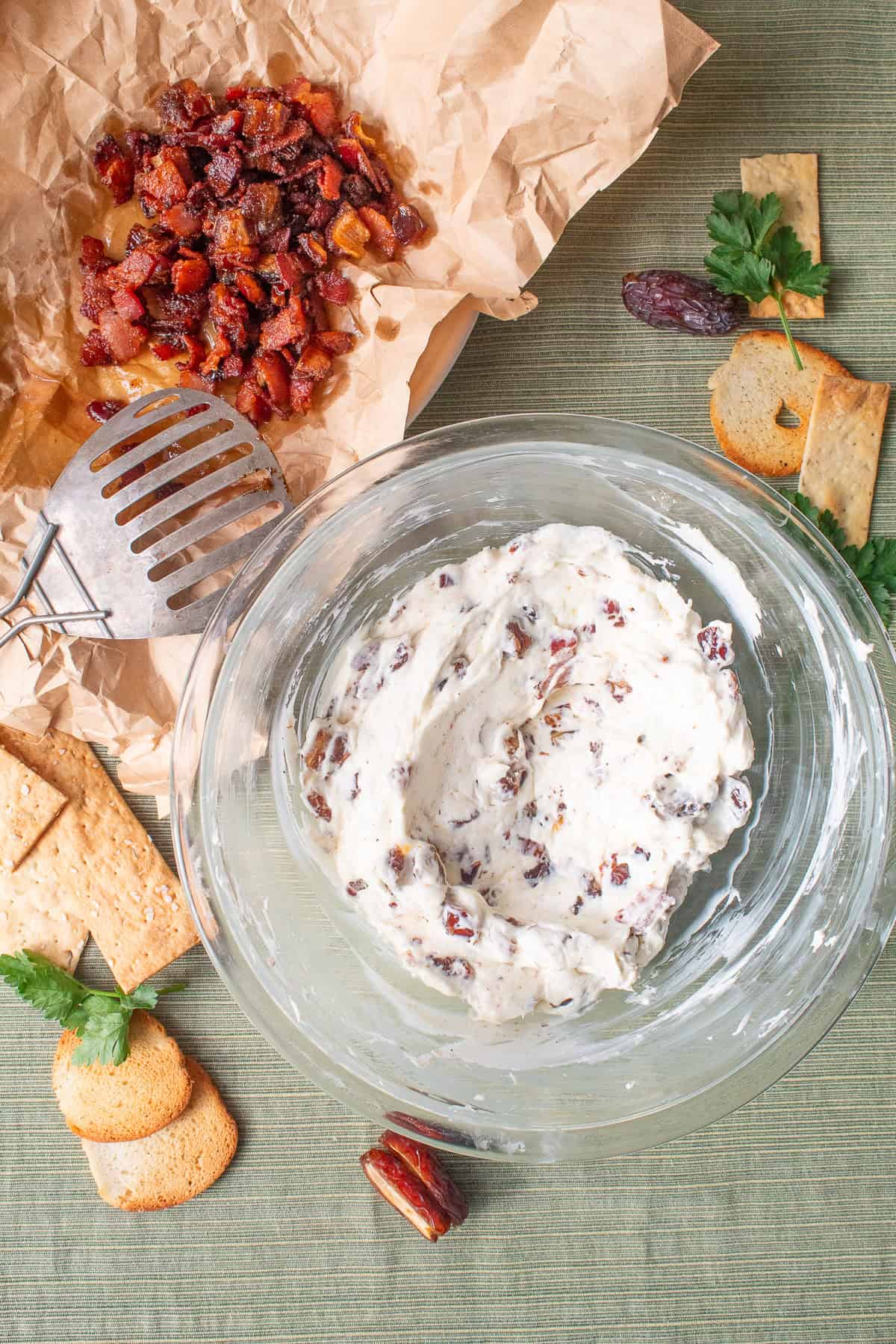 The cheese mixture is stirred together to create a smooth spread studded with bacon, dates, and black pepper.