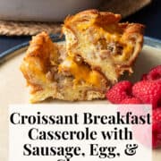 A baked croissant is sliced in half to reveal the tender filling of eggs, cheese, and sausage and a crisp and flaky exterior. A white text box at the bottom of the image contains the words, :croissant breakfast casserole with sausage, egg & cheese" and "plan. eat. post. repeat."