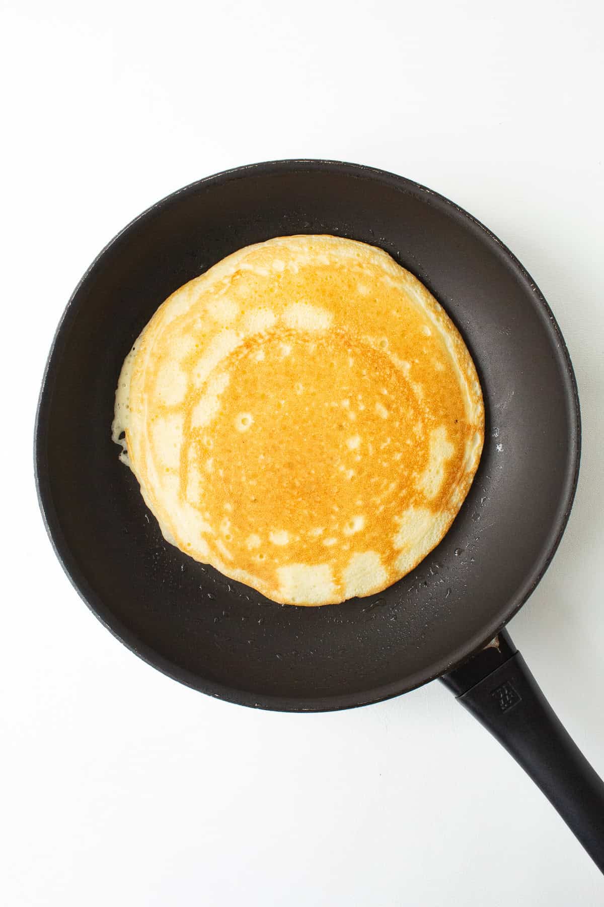 The pancake is flipped, revealing a golden side.