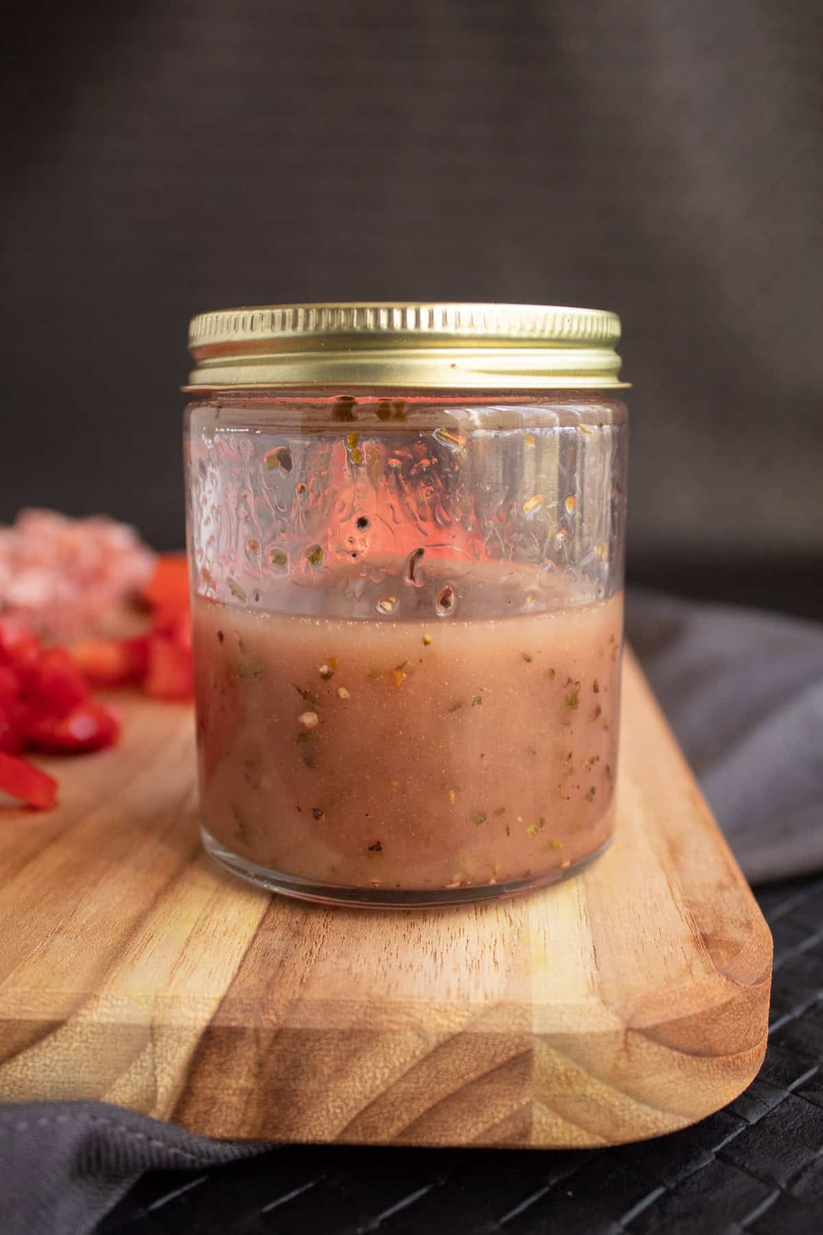 The salad dressing is shaken in a lidded jar to combine the oil, vinegar, oregano, salt, and pepper.