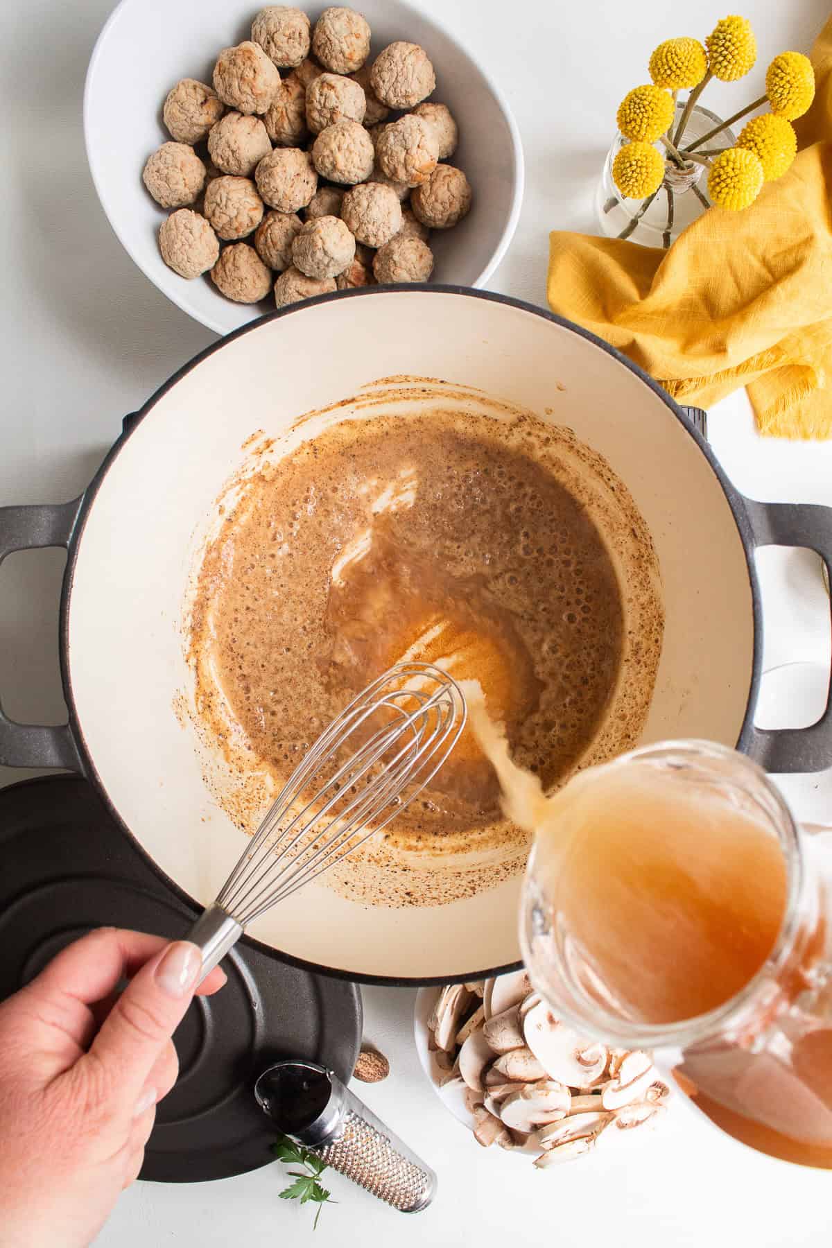 Beef stock is whisked into the cooked flour and spice mixture.