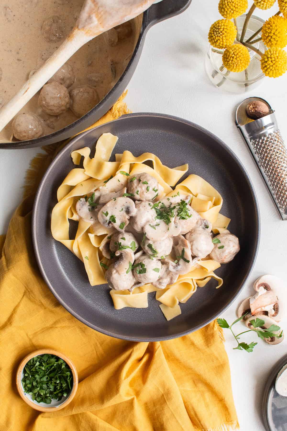 A gray plate is piled with noodles and then the meatballs in a pale brown gravy are ladled over the top.