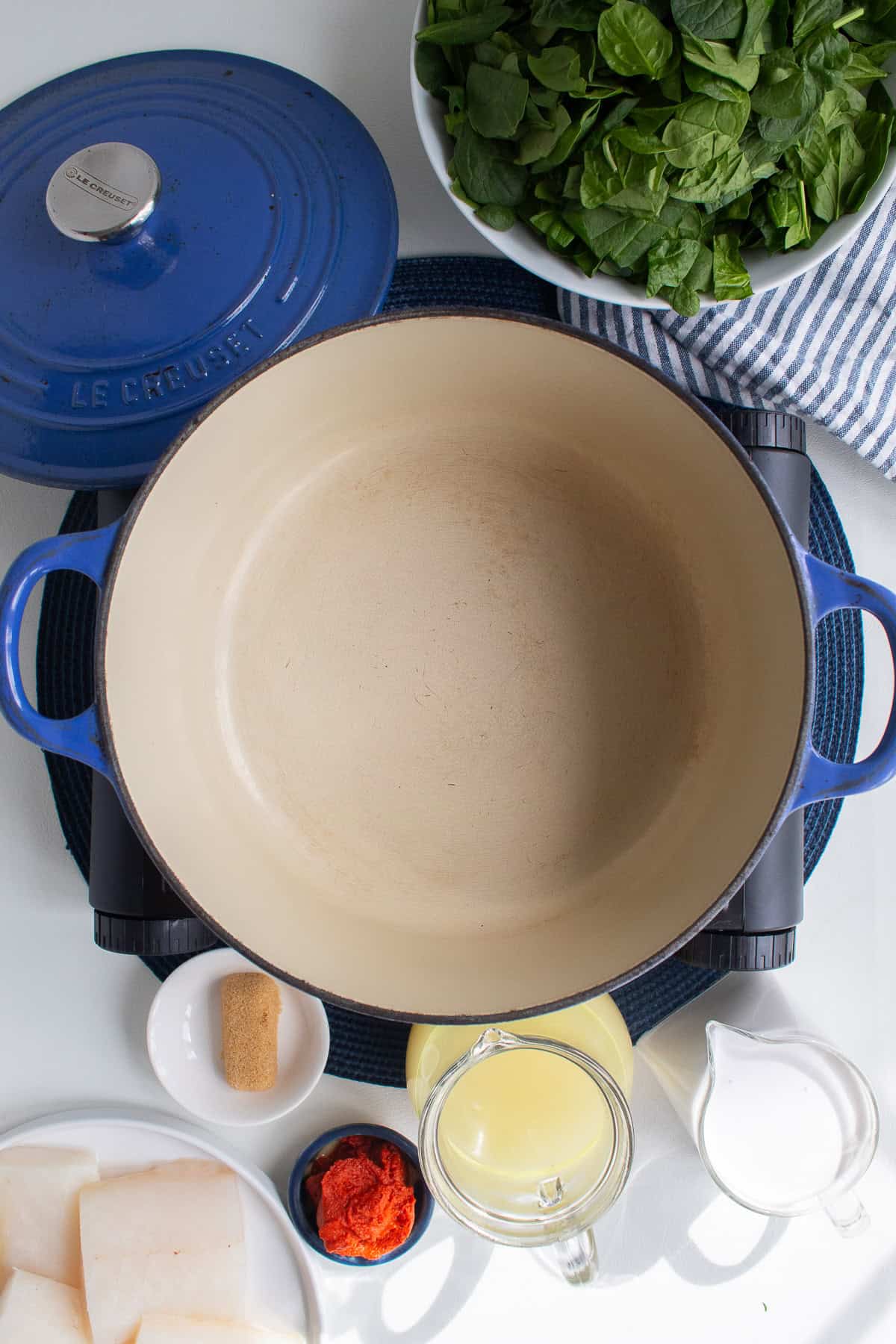 A Dutch oven is surrounded by the fish curry ingredients.