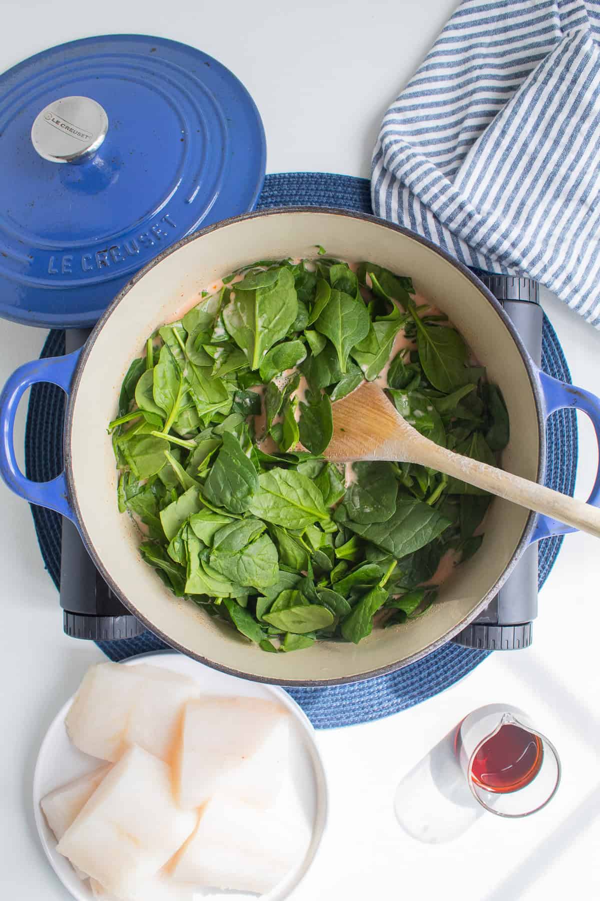 Roughly chopped spinach is added to the coconut curry sauce to be wilted.