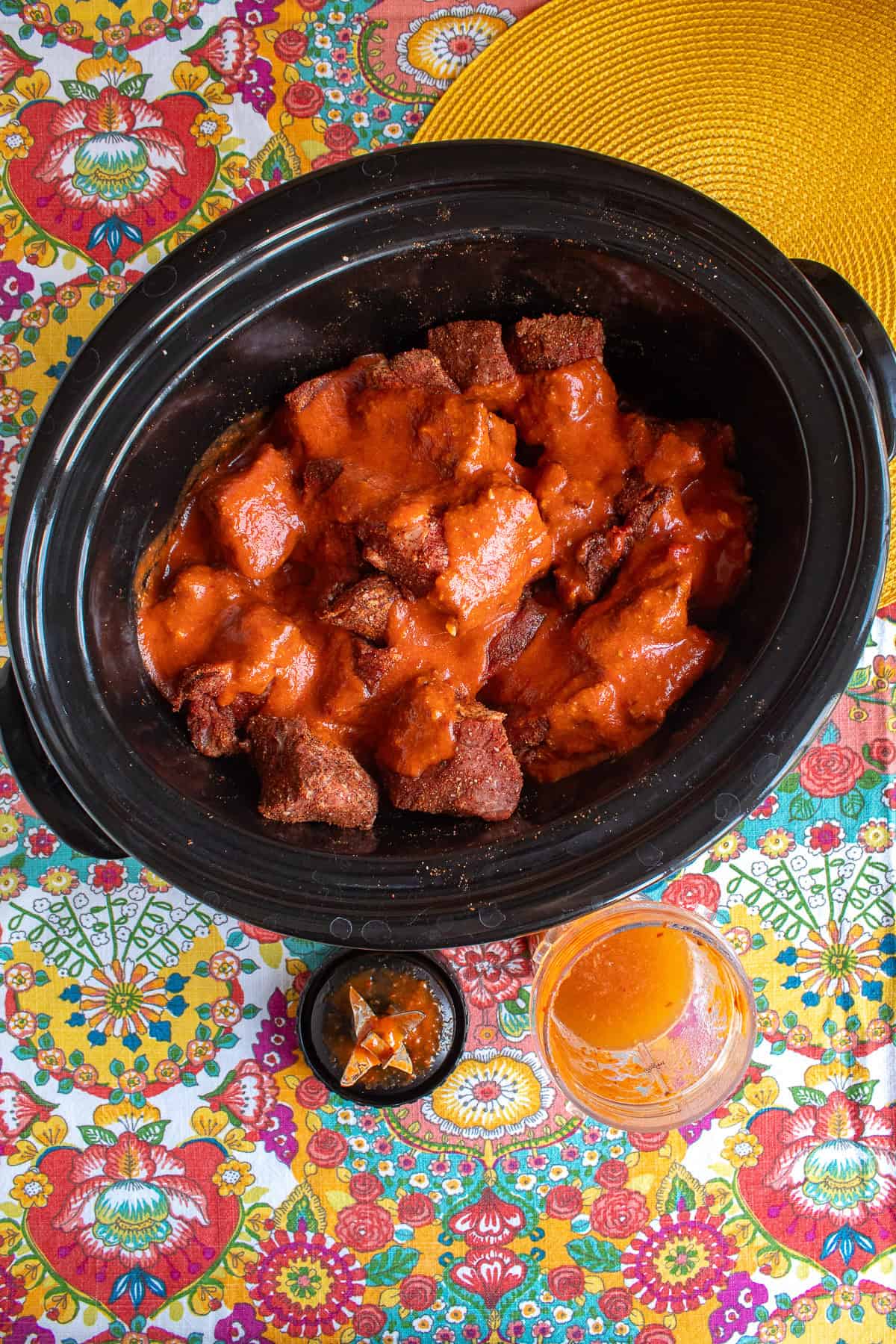 The chipotle, garlic, and tomato sauce is poured over the seasoned beef chuck cubes in the slow cooker crock.
