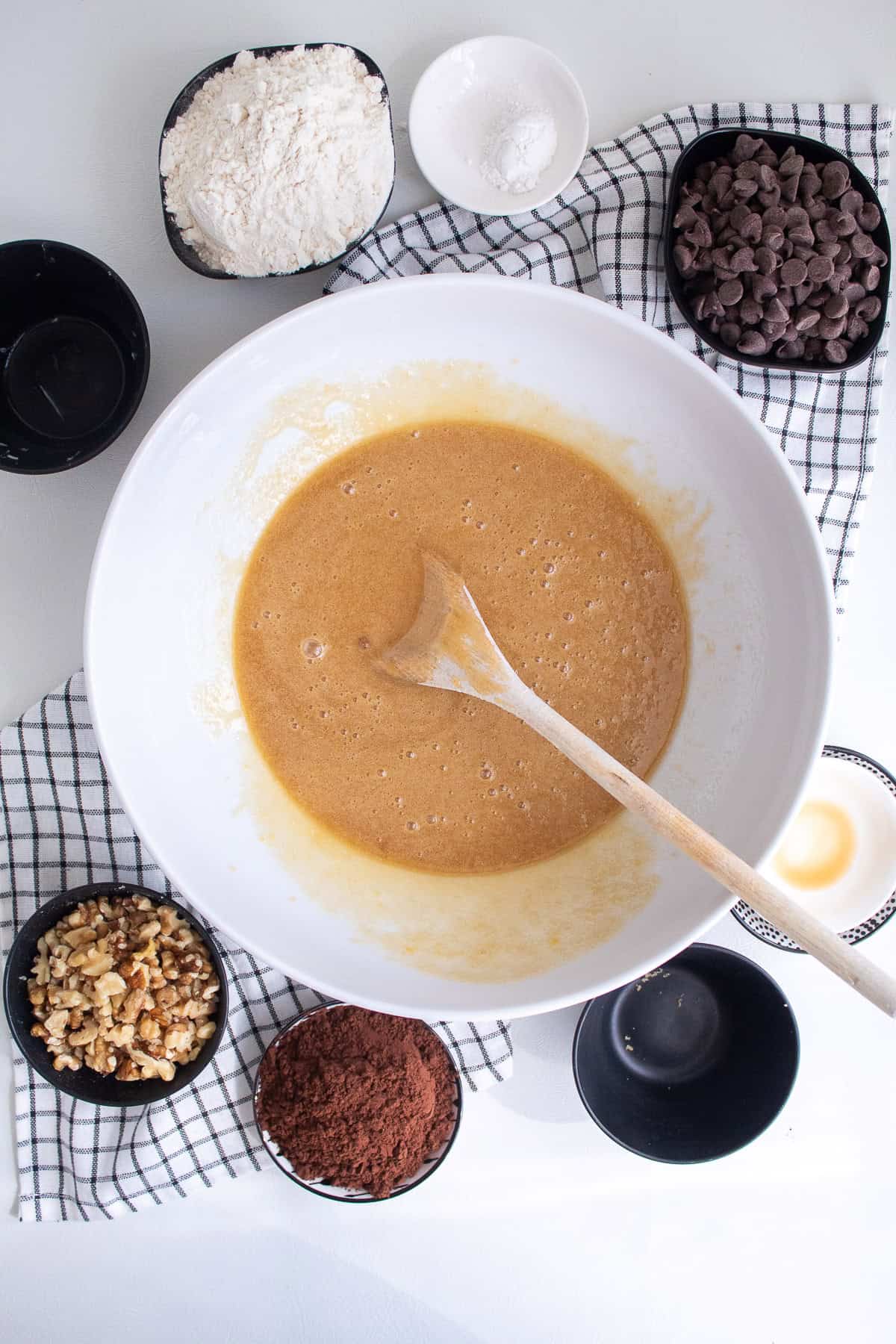 A large white bowl contains the mixed wet ingredients of the cookie dough.